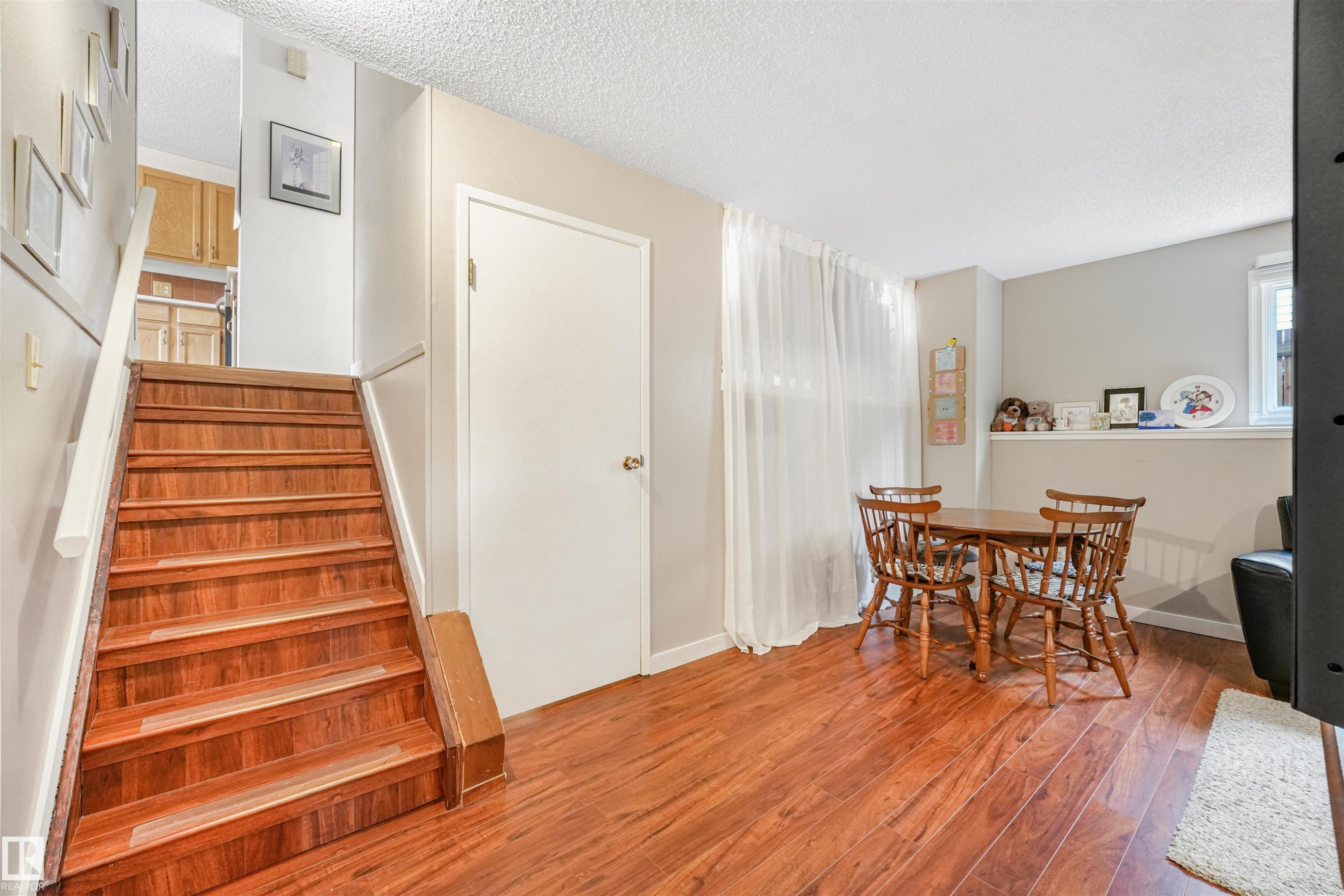 Wood-finish flooring throughout, featuring a staircase with white handrails - 18611 57 Avenue Nw, Edmonton, AB - Indoor