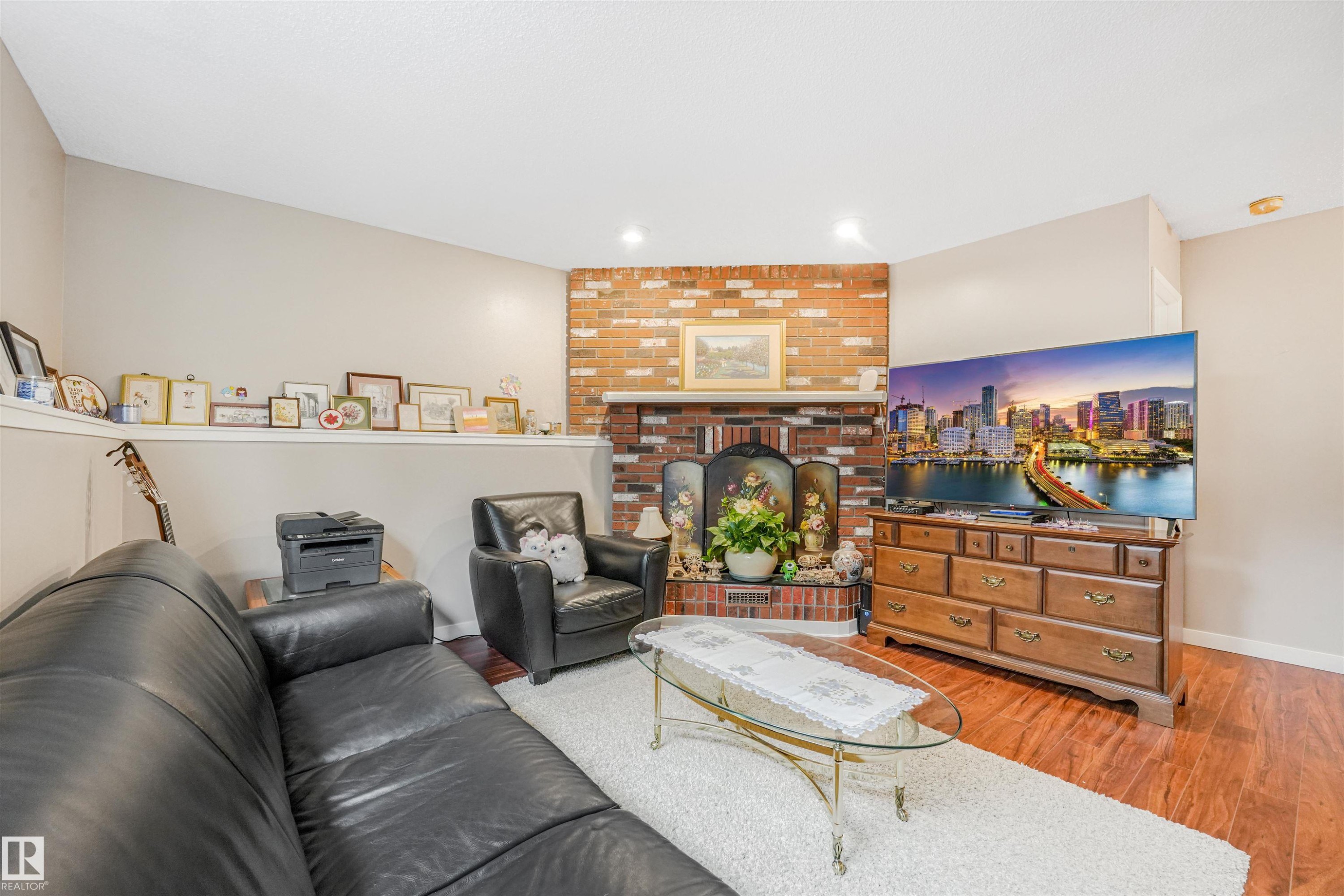 Living area featuring a brick fireplace, wood-finish flooring, recessed lighting, and a built-in wall shelf - 18611 57 Avenue Nw, Edmonton, AB - Indoor