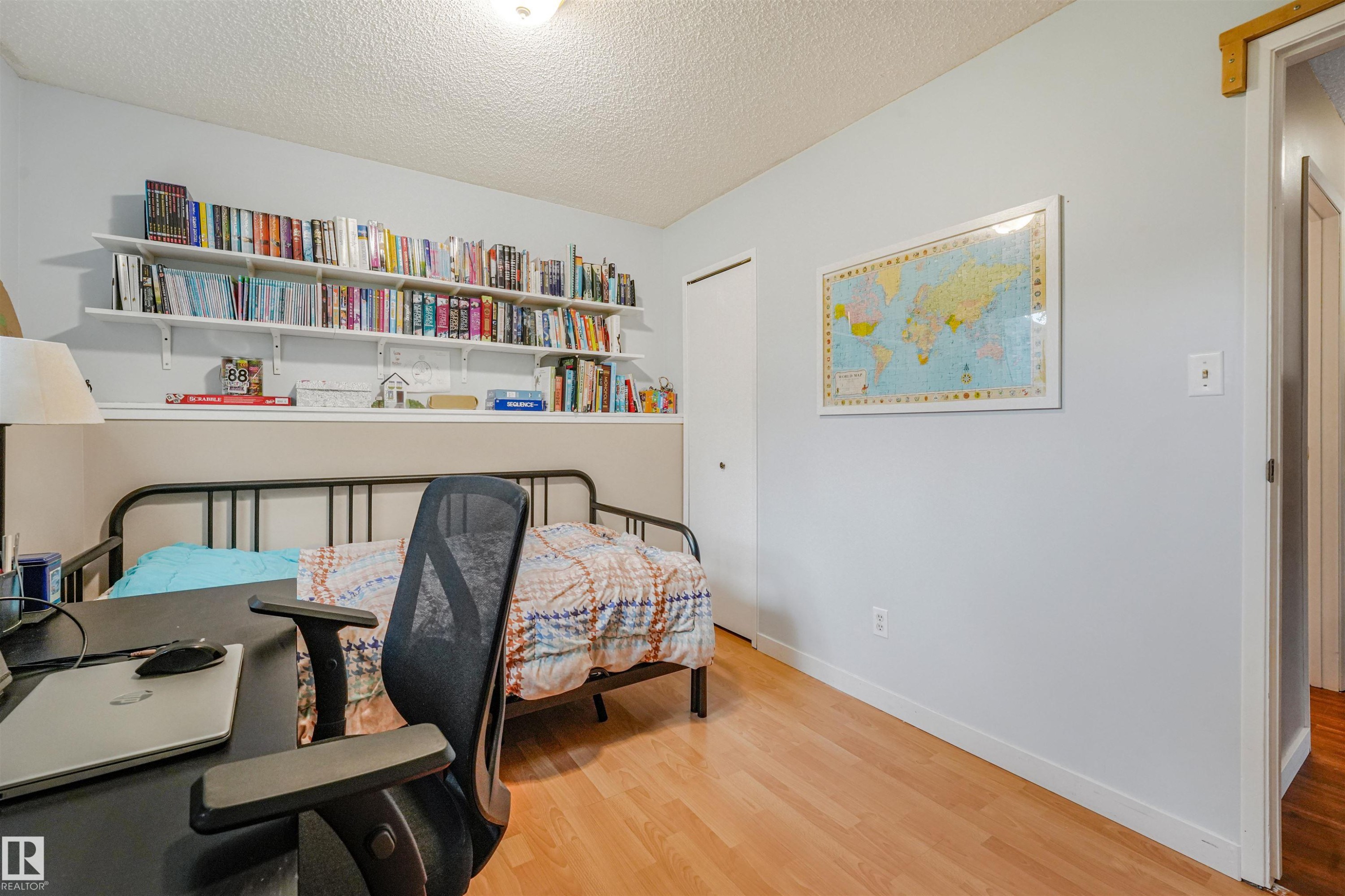 Room featuring wood-finish flooring, a built-in shelving system, and a flush-mount ceiling light - 18611 57 Avenue Nw, Edmonton, AB - Indoor