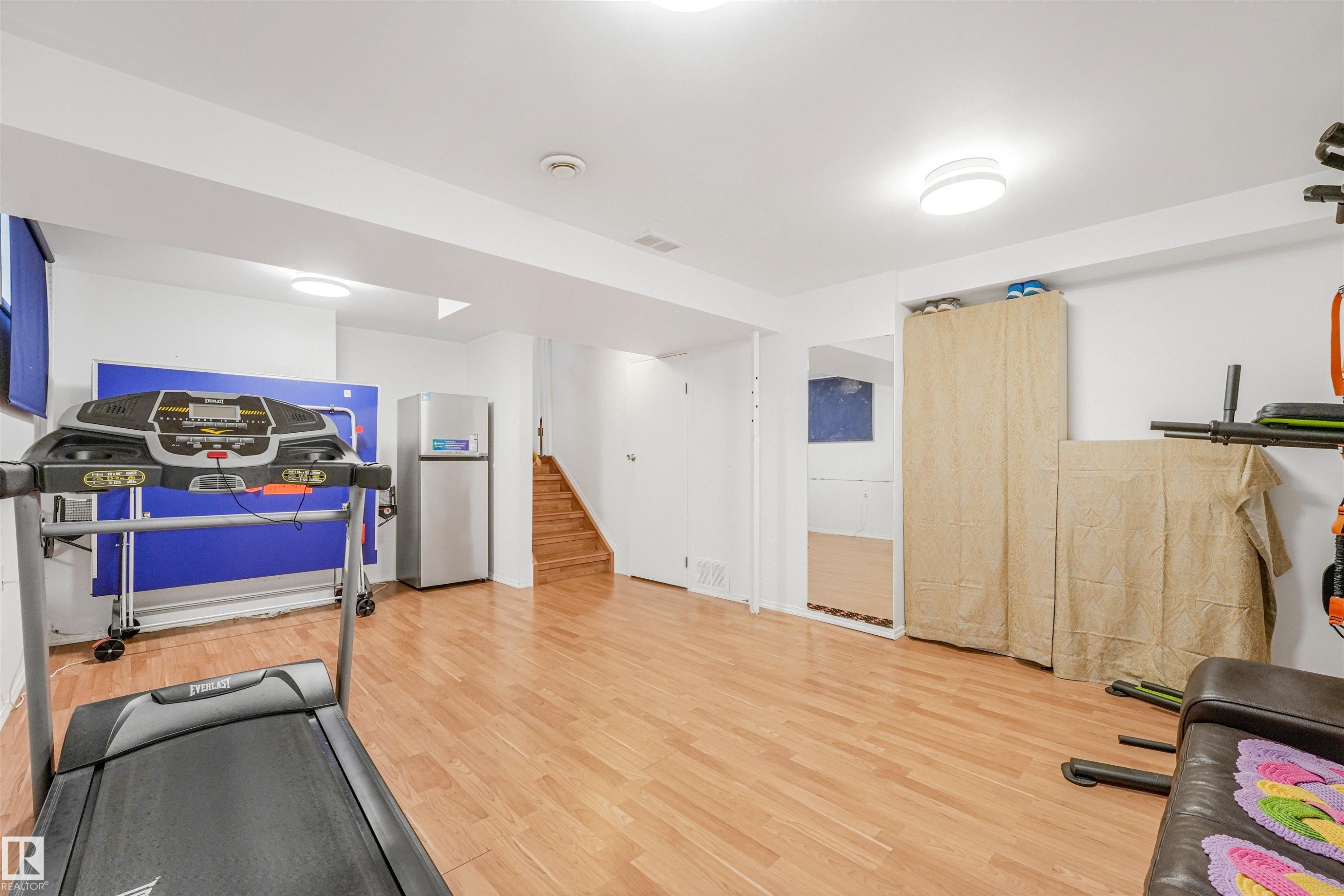 Spacious room featuring wood-finish flooring, white walls, and recessed lighting - 18611 57 Avenue Nw, Edmonton, AB - Indoor