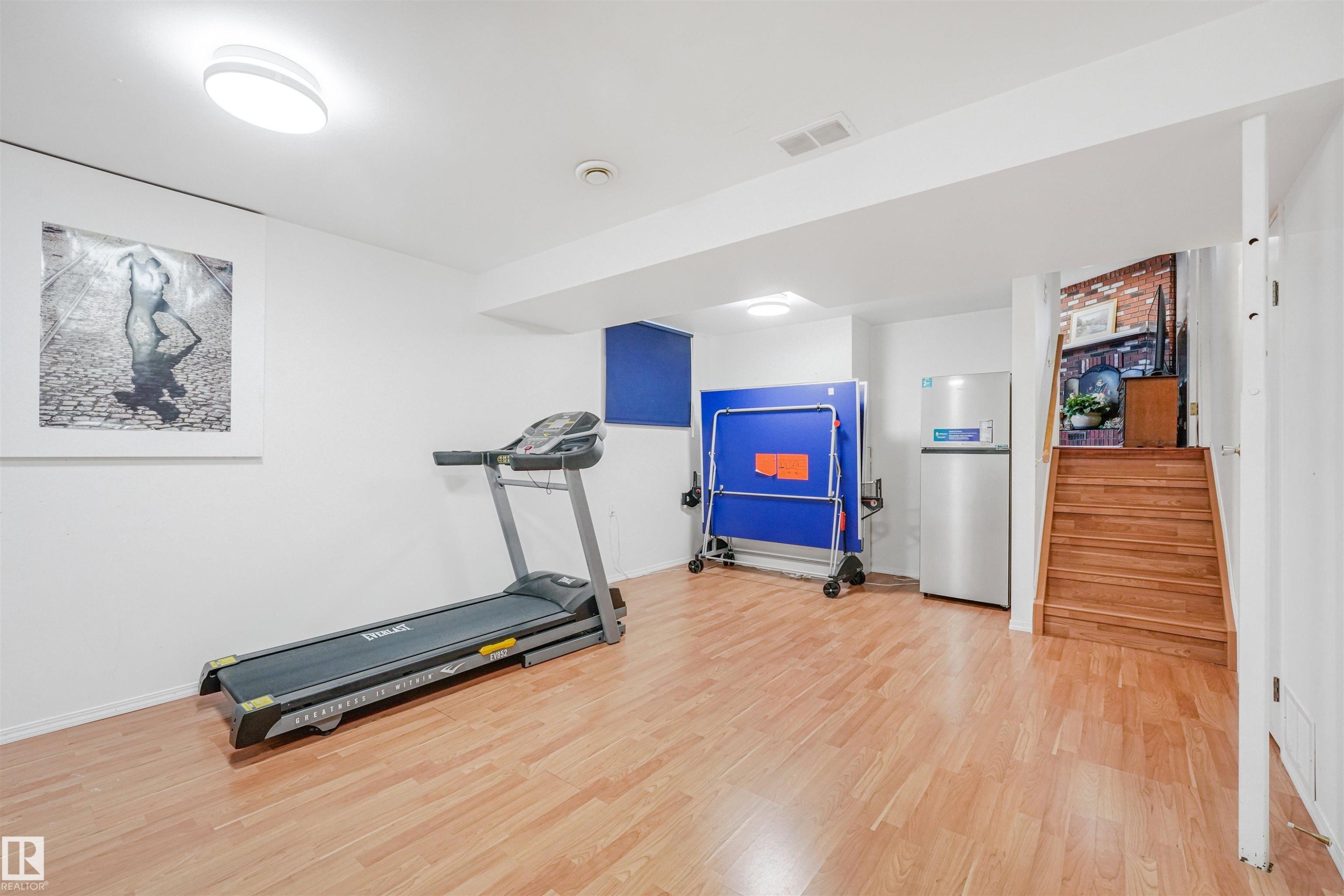 Finished lower level featuring light wood-finish flooring, recessed lighting, and a built-in wooden staircase - 18611 57 Avenue Nw, Edmonton, AB - Indoor Photo Showing Gym Room