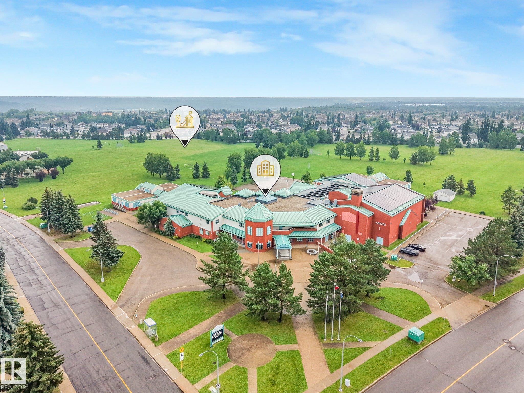 Aerial perspective showcasing a large institutional building with a red brick facade and green roofing - 18611 57 Avenue Nw, Edmonton, AB - Outdoor With View