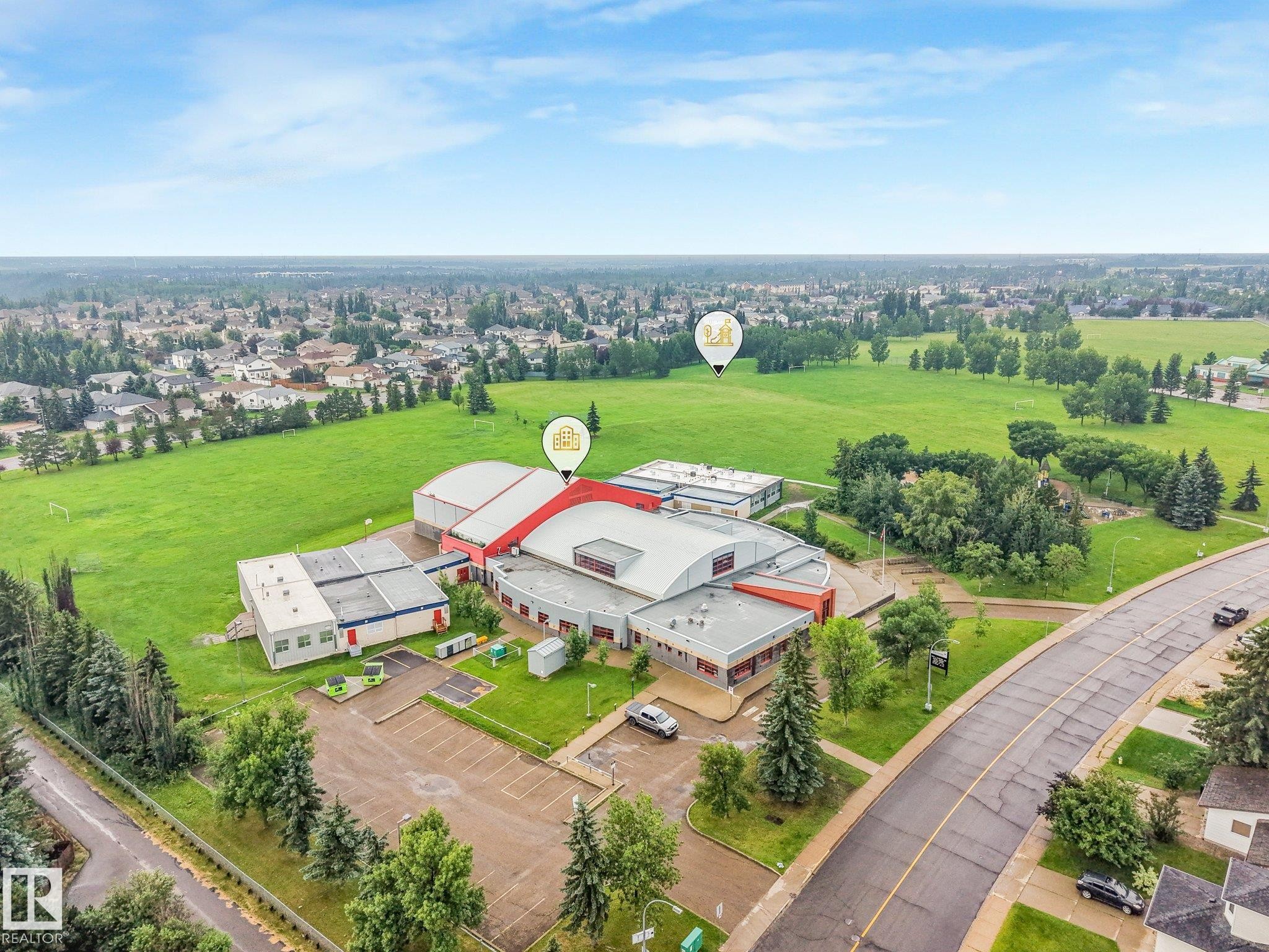 Spacious commercial building featuring a large parking lot, expansive green spaces, and a surrounding residential area - 18611 57 Avenue Nw, Edmonton, AB - Outdoor With View
