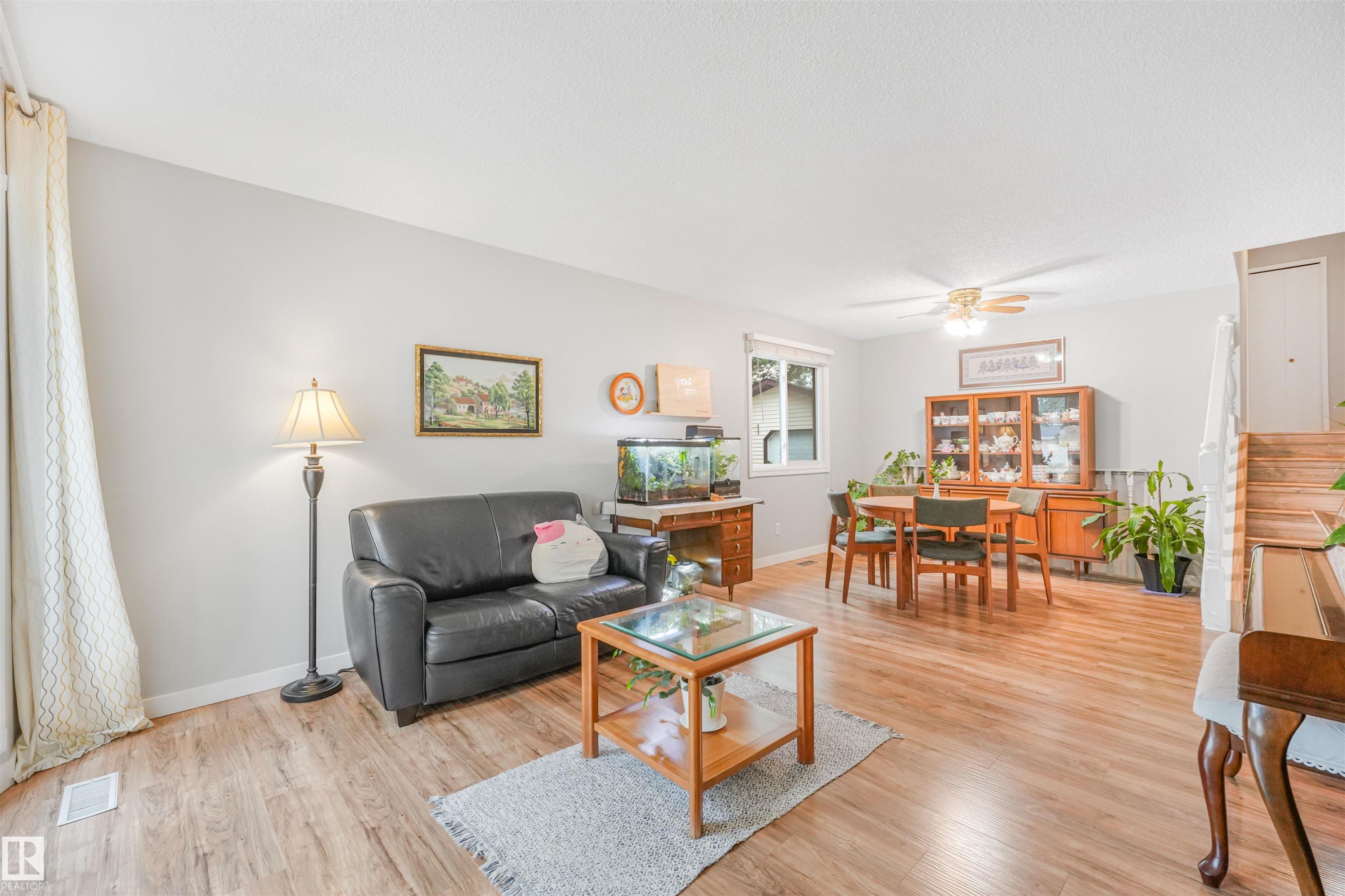 Open-concept living space featuring wood-finish flooring, light grey wall paint, and a ceiling fan - 18611 57 Avenue Nw, Edmonton, AB - Indoor Photo Showing Living Room