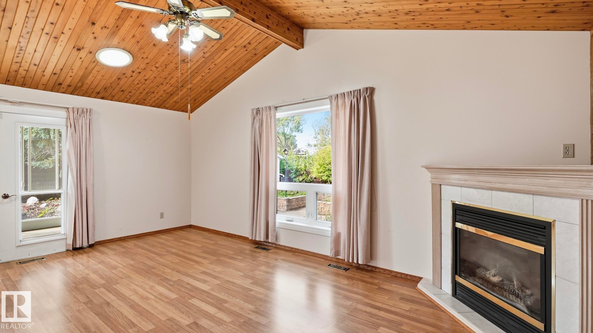 Vaulted wood-paneled ceiling, recessed circular lighting, wood-finish flooring, fireplace with tiled surround, and multiple windows - 8408 176 Street Nw, Edmonton, AB - Indoor With Fireplace