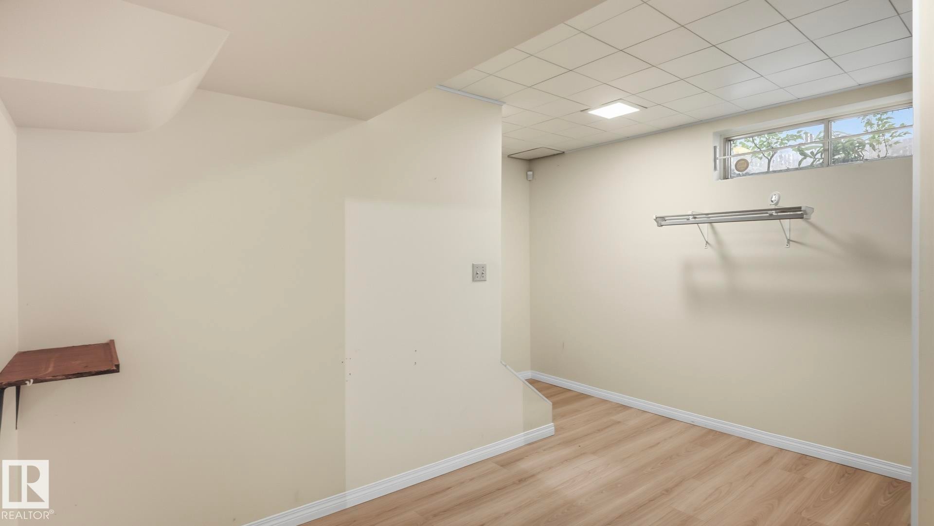 Wood-finish flooring, drop ceiling with recessed lighting, and a basement window - 8408 176 Street Nw, Edmonton, AB - Indoor