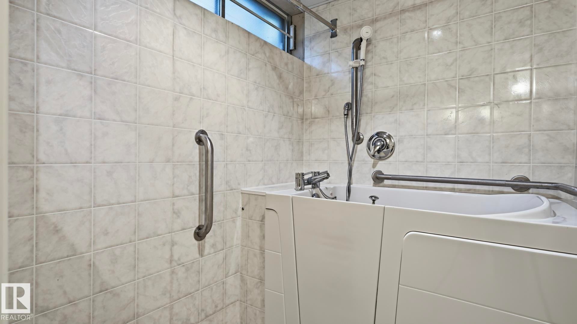 Walk-in bathtub with chrome fixtures, tiled walls, and grab bars - 8408 176 Street Nw, Edmonton, AB - Indoor Photo Showing Bathroom