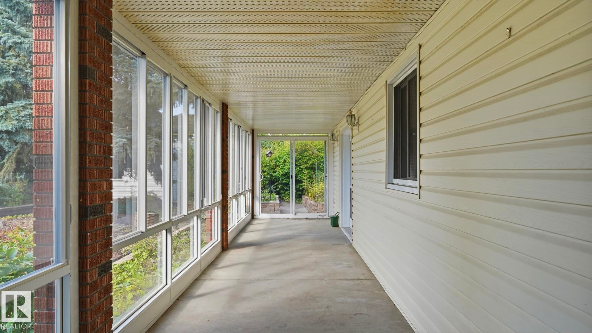 Enclosed sunroom featuring a concrete floor, brick column accents, and a paneled ceiling - 8408 176 Street Nw, Edmonton, AB - Outdoor With Exterior