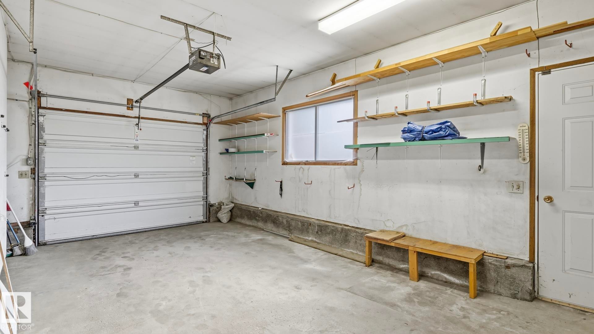 Attached garage featuring a concrete floor, automatic garage door opener, and integrated shelving - 8408 176 Street Nw, Edmonton, AB - Indoor Photo Showing Garage