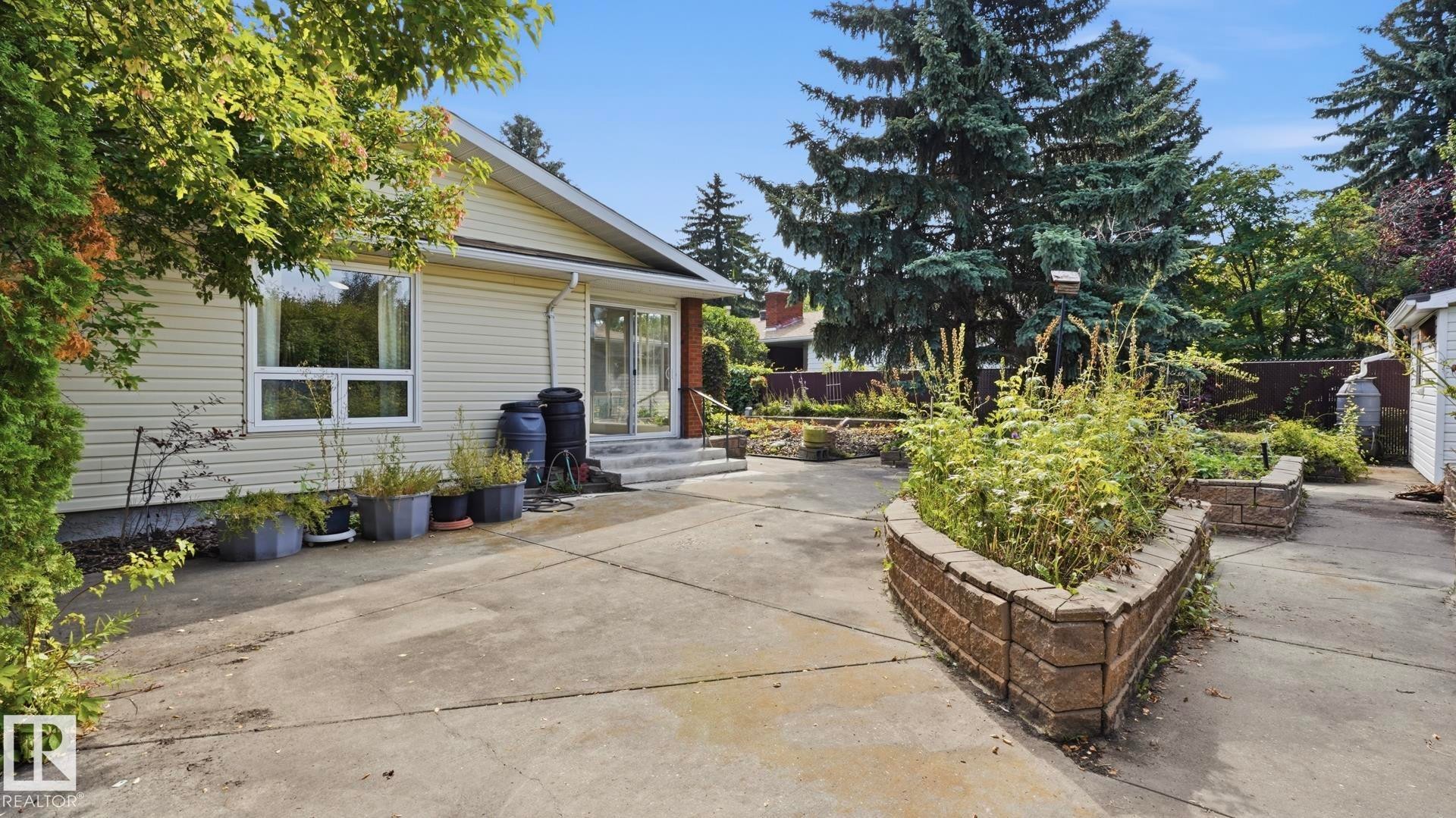 Concrete patio with raised garden beds featuring stacked block retaining walls - 8408 176 Street Nw, Edmonton, AB - Outdoor