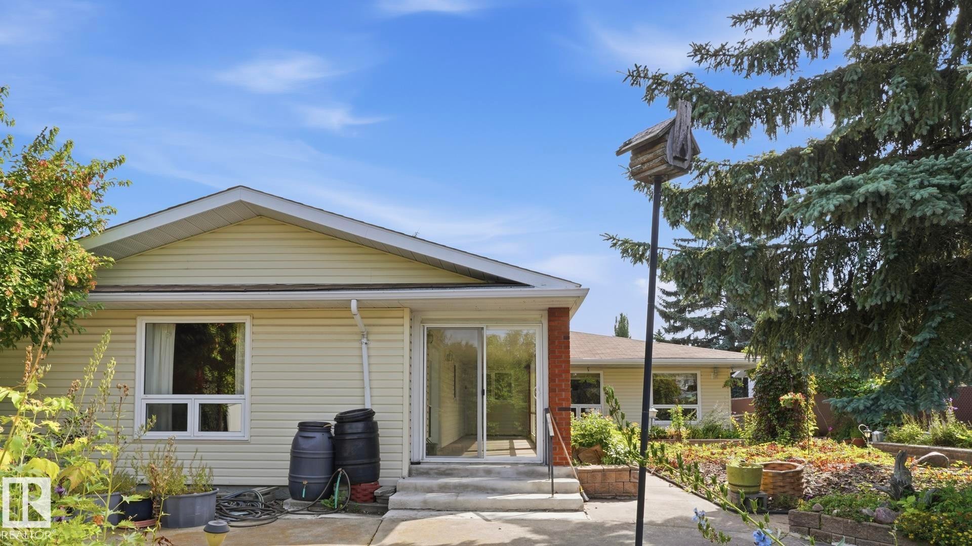 Exterior featuring light-colored siding, multiple windows, and a sliding glass door - 8408 176 Street Nw, Edmonton, AB - Outdoor