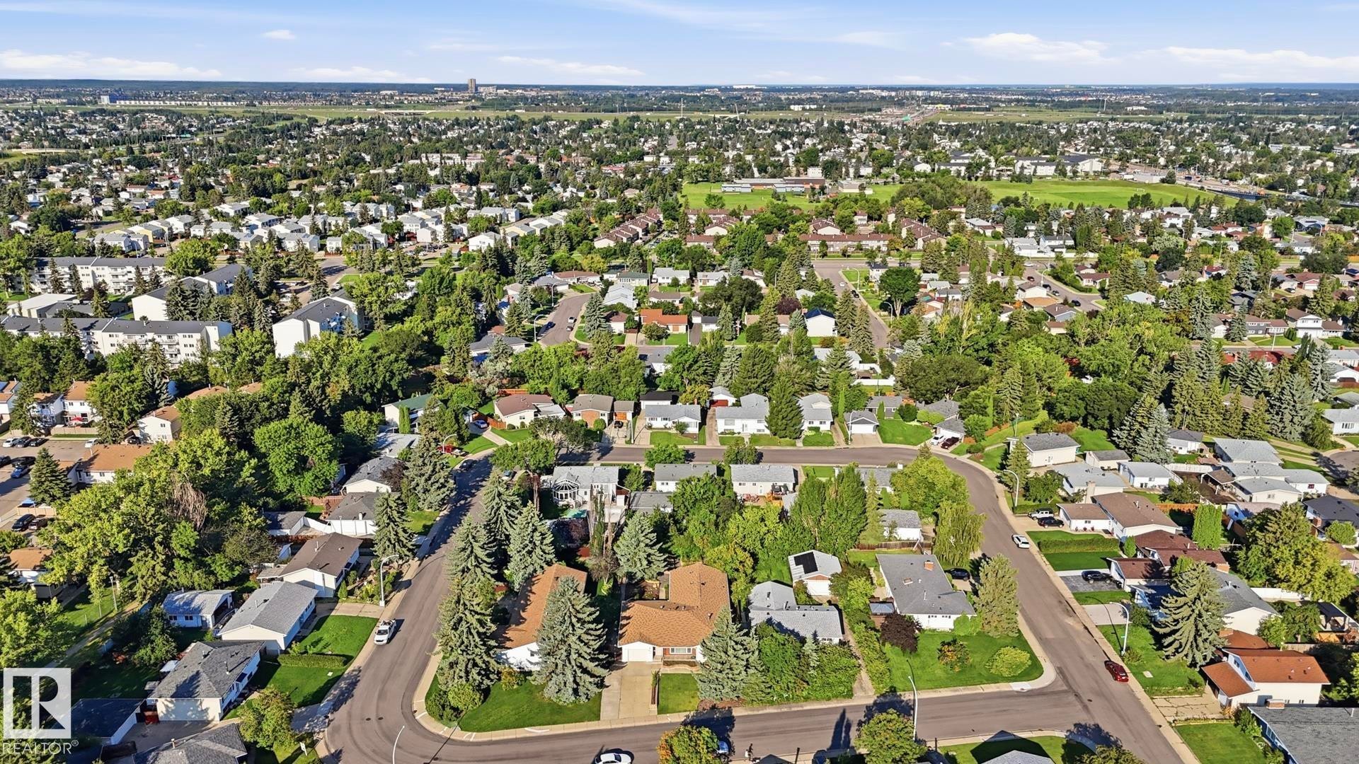 Aerial perspective showcasing a residential neighborhood with mature trees, established streets, and a mix of single-family homes and multi-unit buildings - 8408 176 Street Nw, Edmonton, AB - Outdoor With View