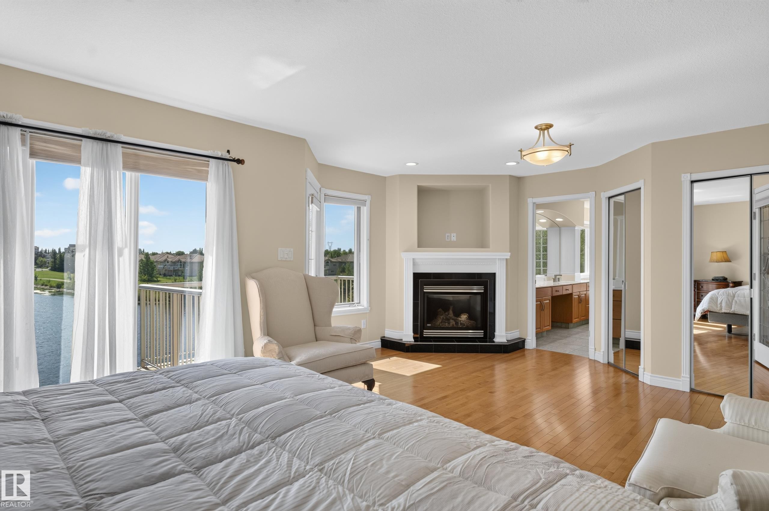 Hardwood flooring, corner fireplace with a white mantel, built-in niche, and glass sliding closet doors - 13527 158 Avenue Nw, Edmonton, AB - Indoor With Fireplace