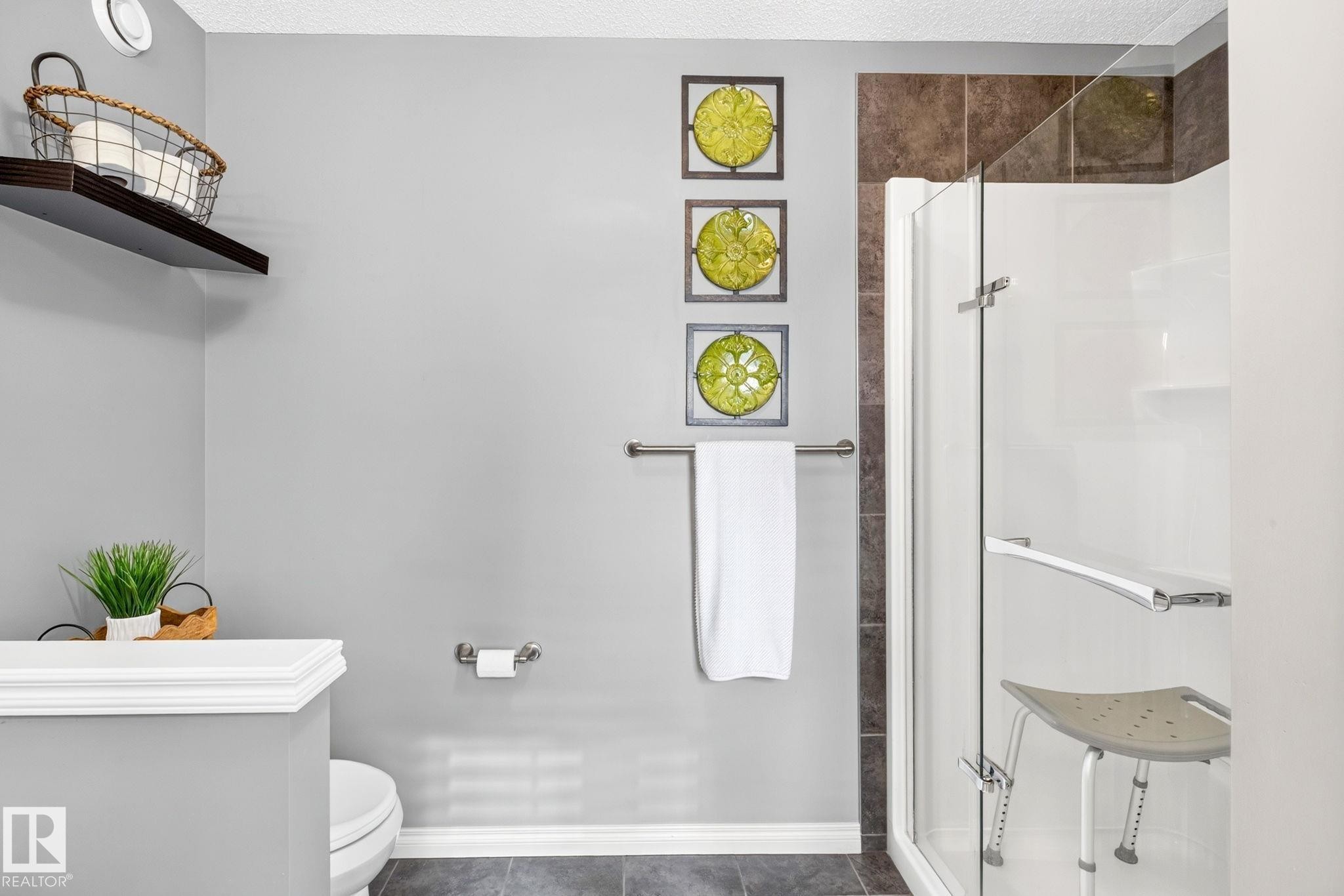 Glass-enclosed shower with a support bar, accompanied by a dark-tiled accent wall - 16512 140 Street Nw, Edmonton, AB - Indoor Photo Showing Bathroom