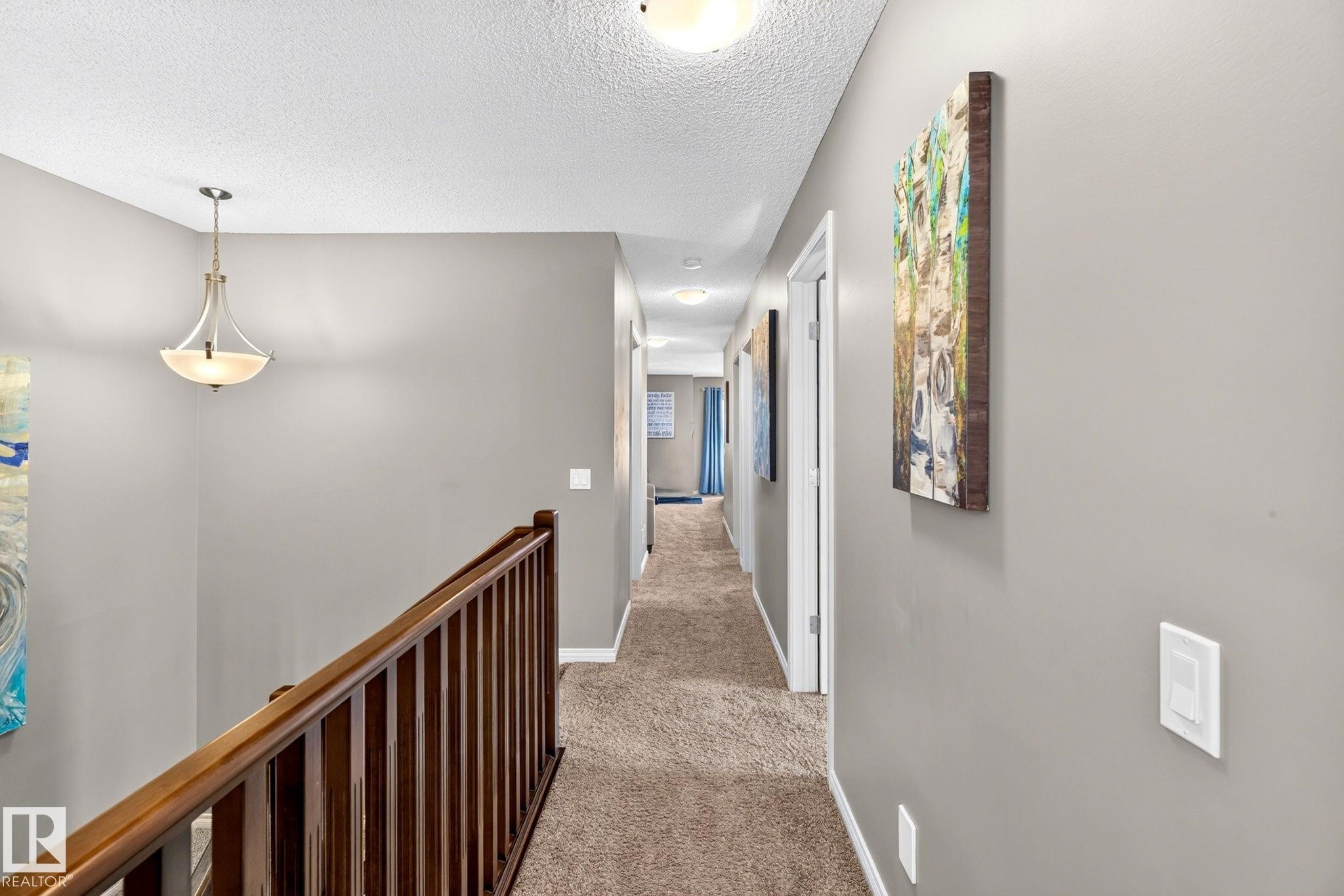 Hallway with wood-finish railing, neutral carpeting, and a semi-flush mount light fixture - 16512 140 Street Nw, Edmonton, AB - Indoor Photo Showing Other Room
