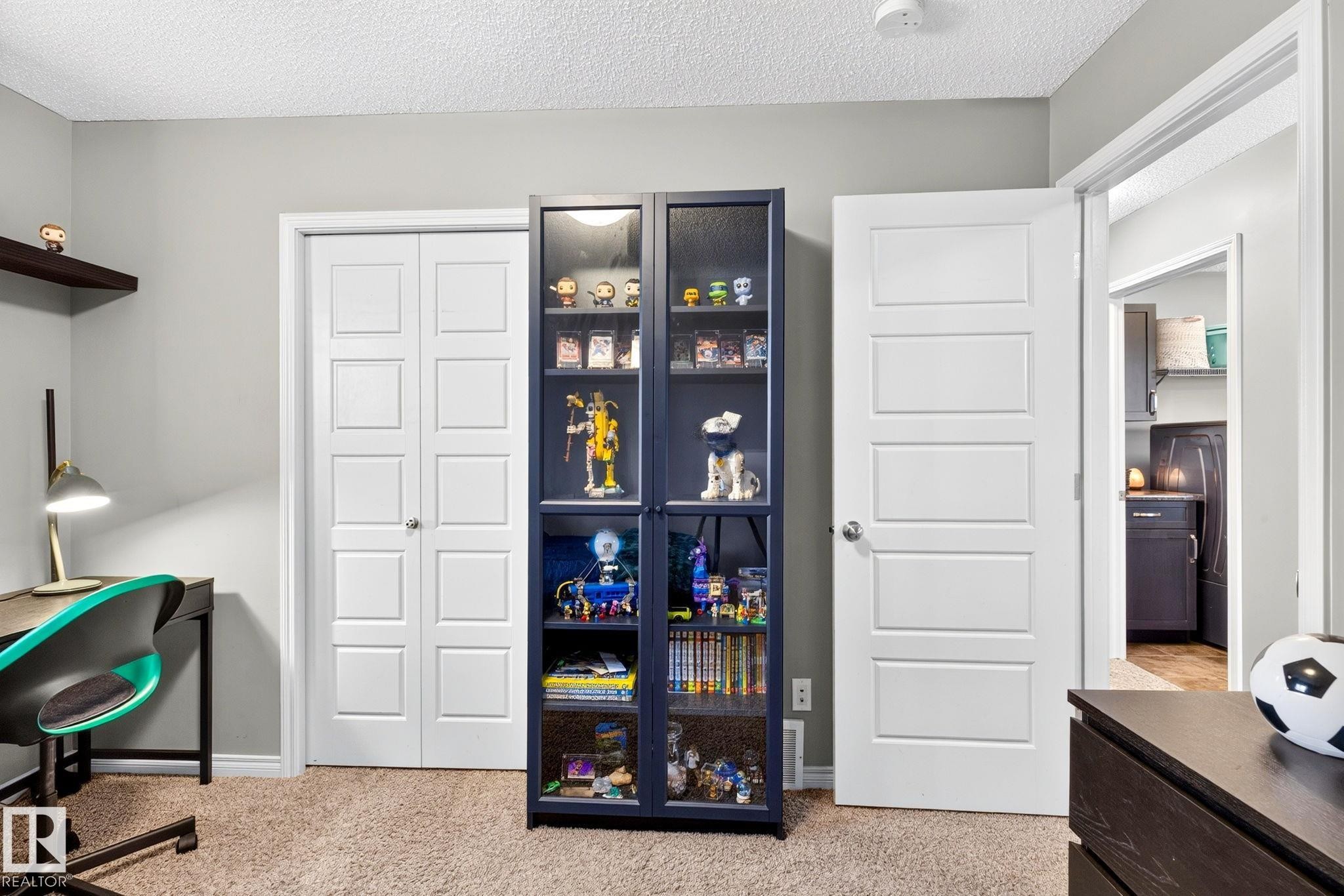 Neutral wall color, wall-mounted shelving, wood-finish flooring, white panel bi-fold closet doors, and white panel interior door - 16512 140 Street Nw, Edmonton, AB - Indoor