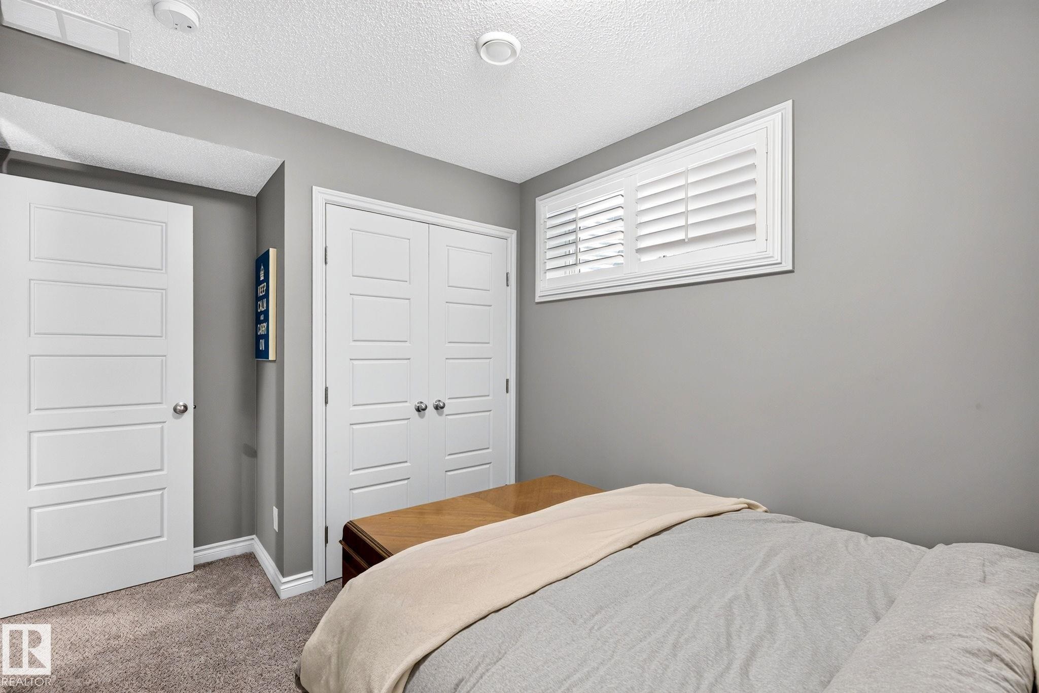 White paneled doors, carpeted flooring, and a white window with louvered shutters - 16512 140 Street Nw, Edmonton, AB - Indoor Photo Showing Bedroom