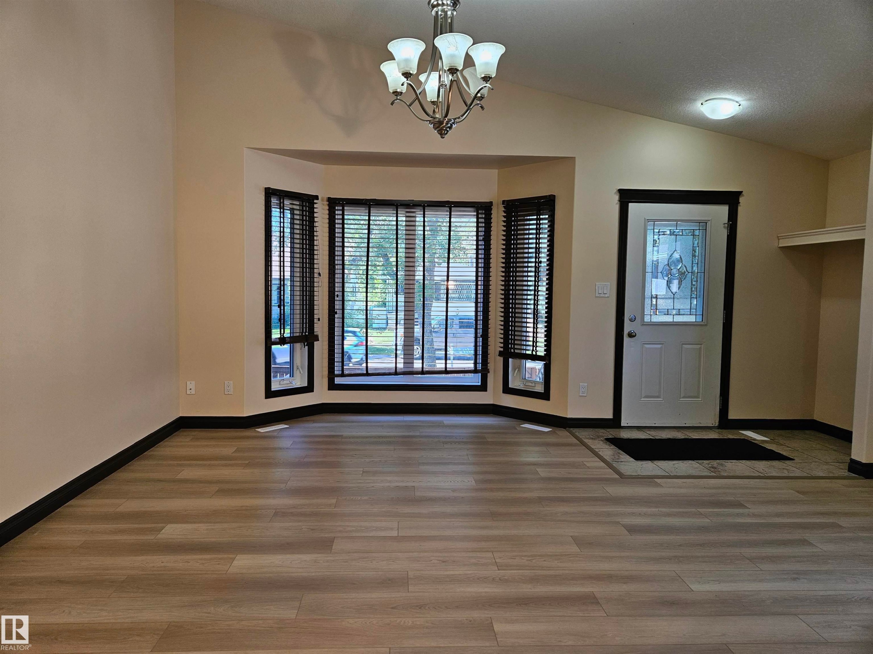 Wood-finish flooring, bay window with blinds, decorative front door, vaulted ceiling, and built-in shelving - 11625 88 Street Nw, Edmonton, AB