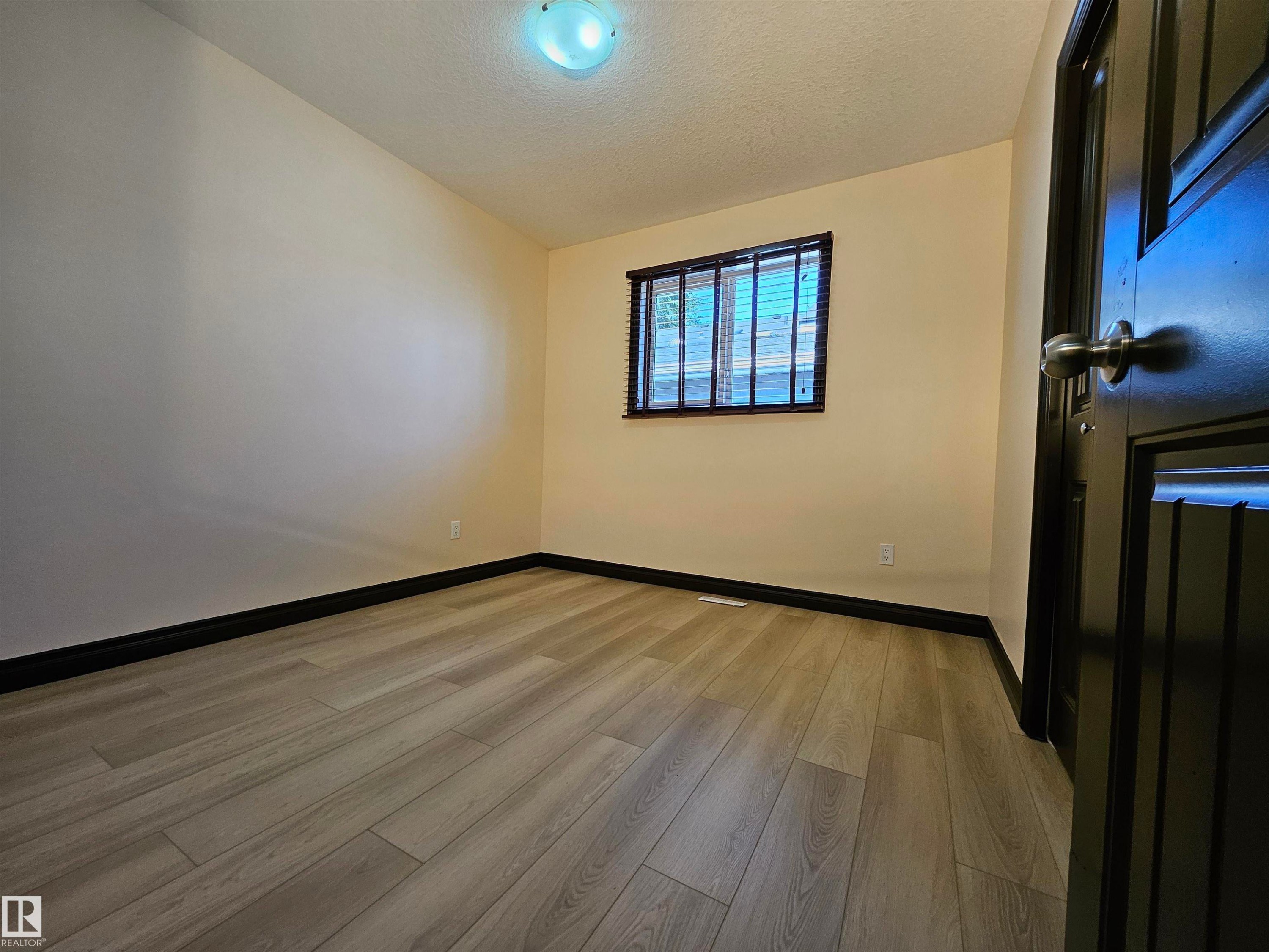 Wood-finish flooring, dark trim, and light wall finishes - 11625 88 Street Nw, Edmonton, AB