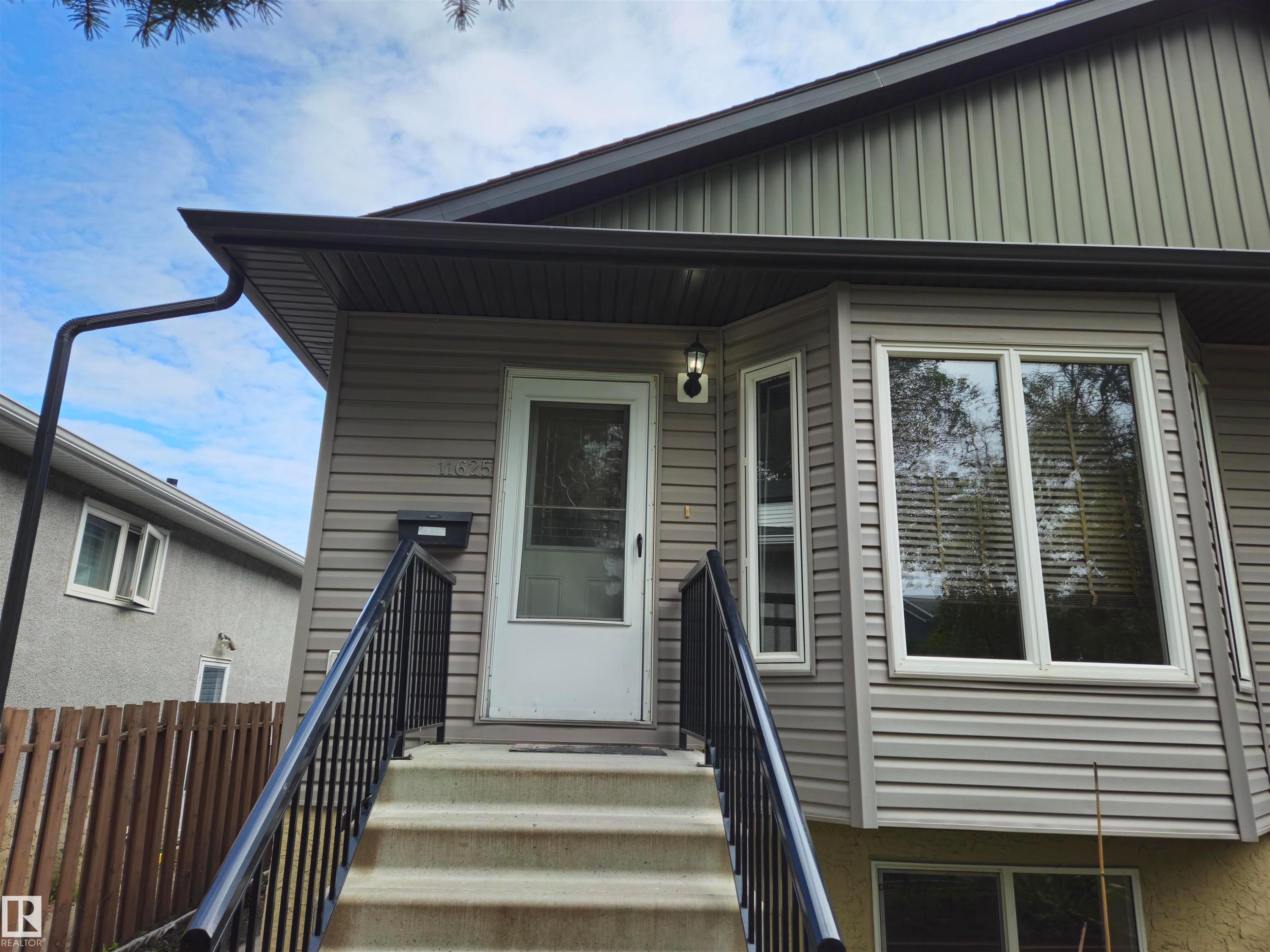 Bay window with white trim, gray siding, and a white entrance door - 11625 88 Street Nw, Edmonton, AB