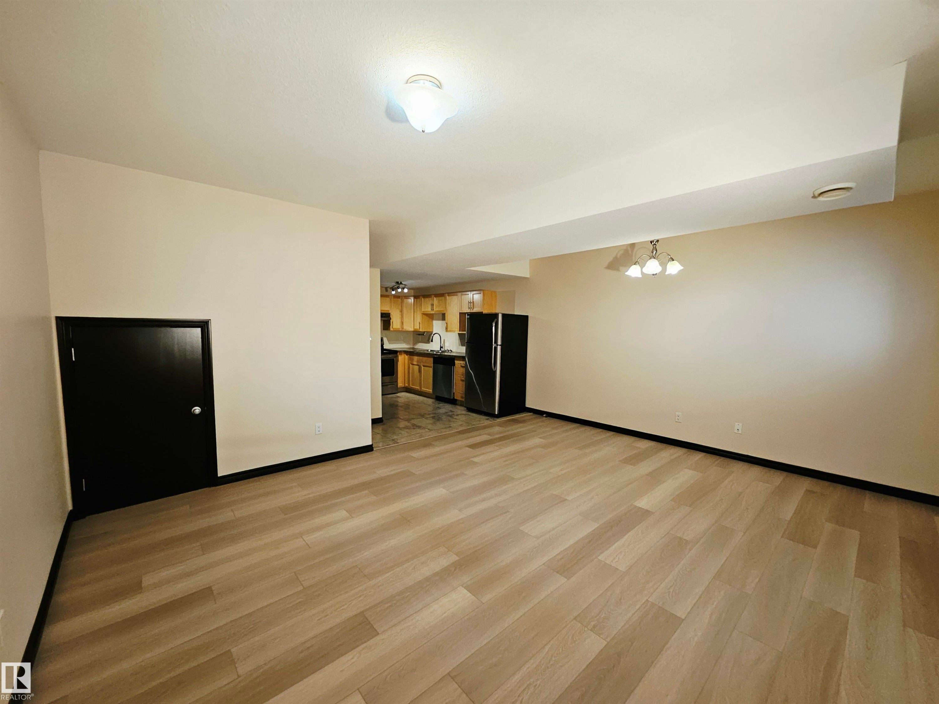 Spacious living area featuring light wood-finish flooring - 11625 88 Street Nw, Edmonton, AB