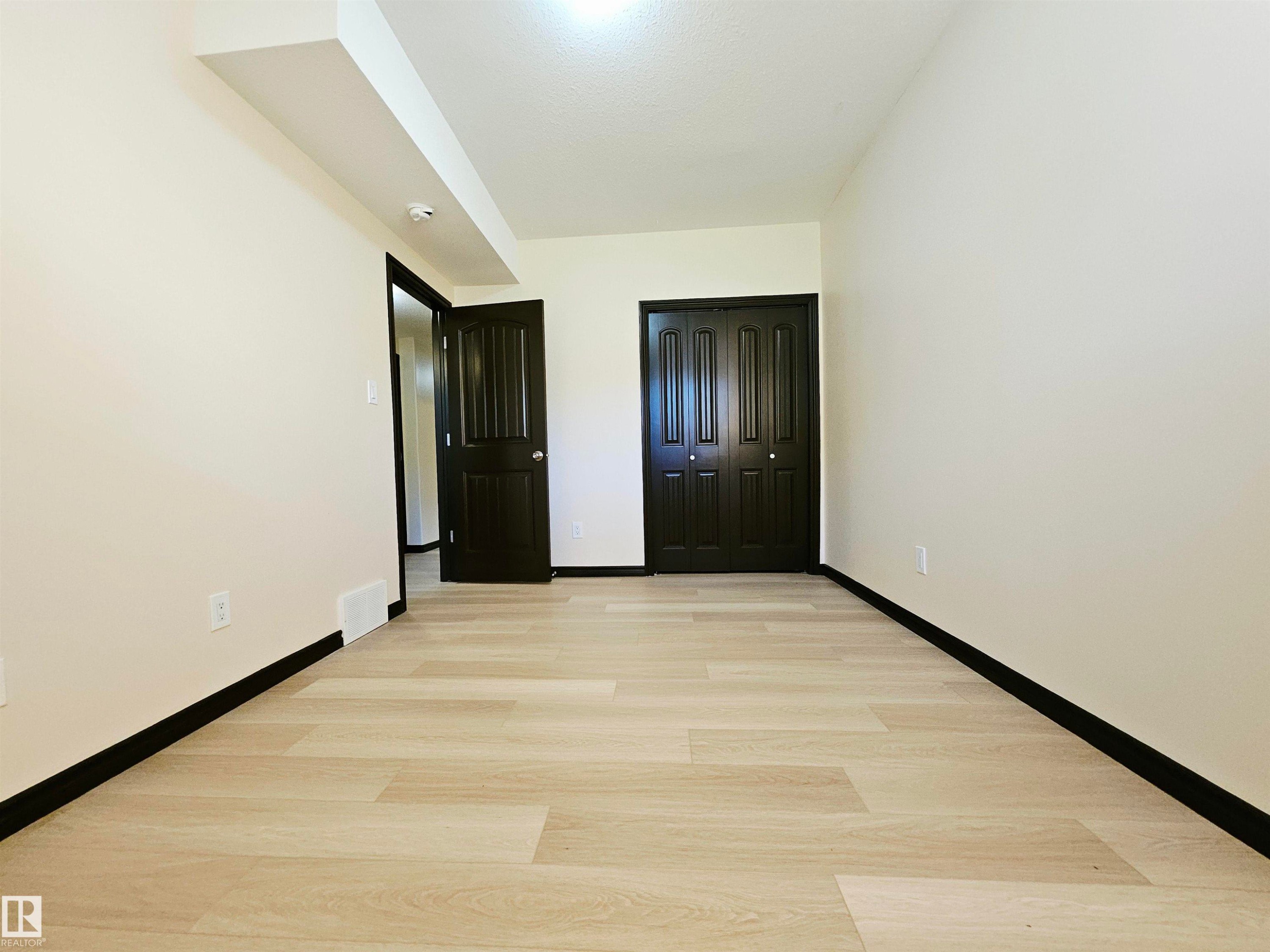 Light wood-finish flooring with dark trim - 11625 88 Street Nw, Edmonton, AB