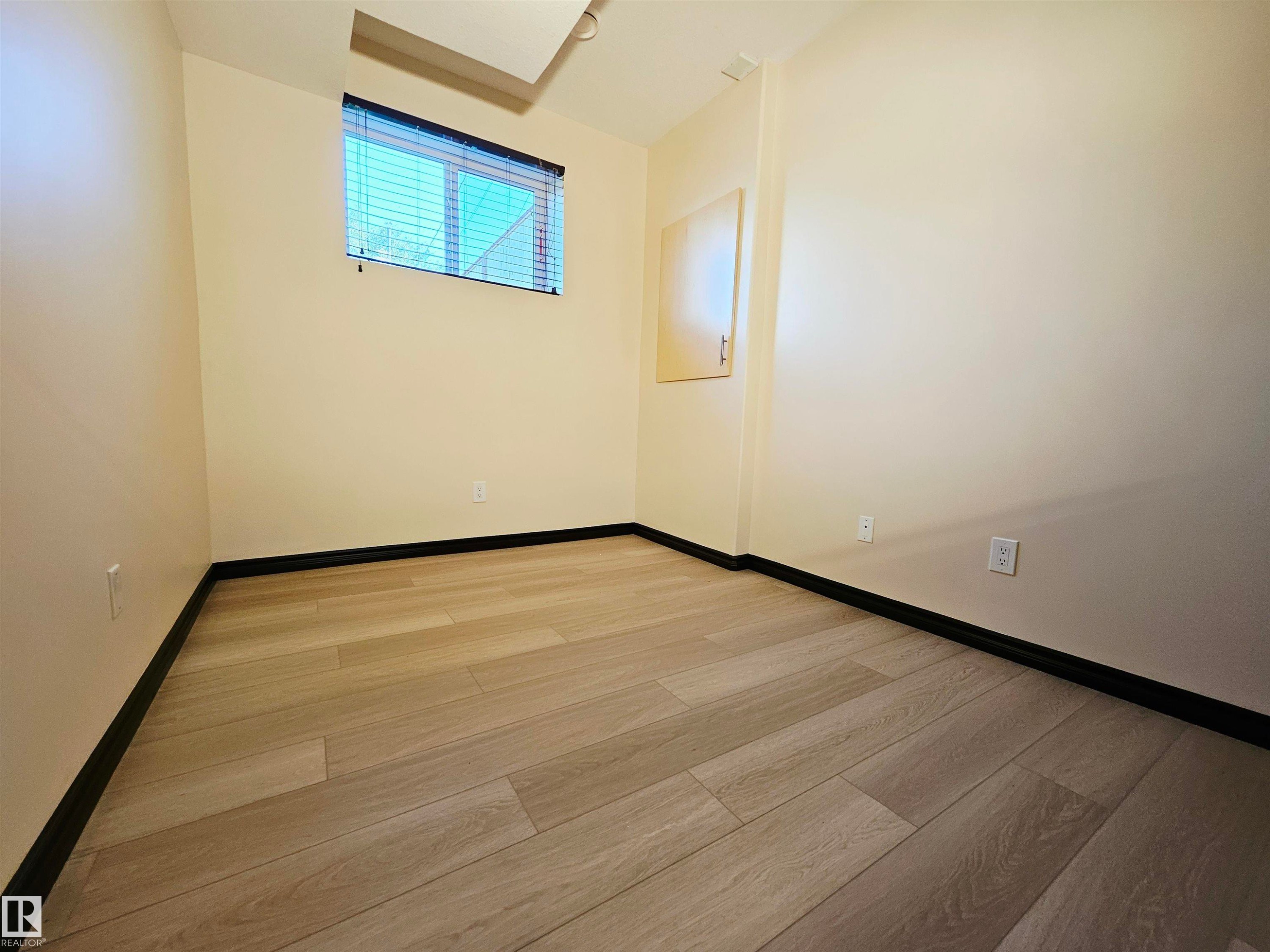 Wood-finish flooring with black trim, light-toned walls, and a window with blinds - 11625 88 Street Nw, Edmonton, AB