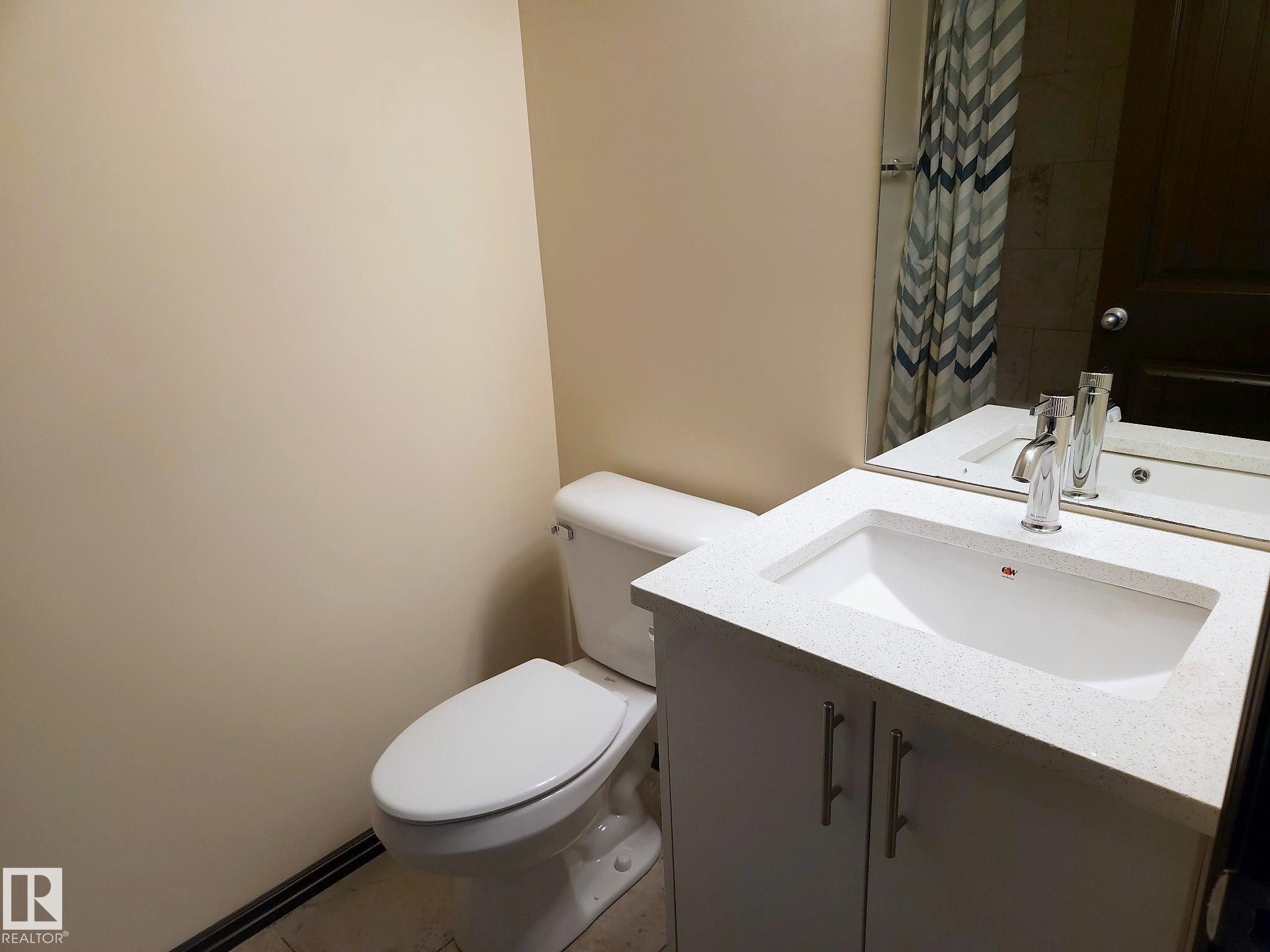 White vanity with a light-toned countertop, undermount sink, and chrome faucet - 11625 88 Street Nw, Edmonton, AB