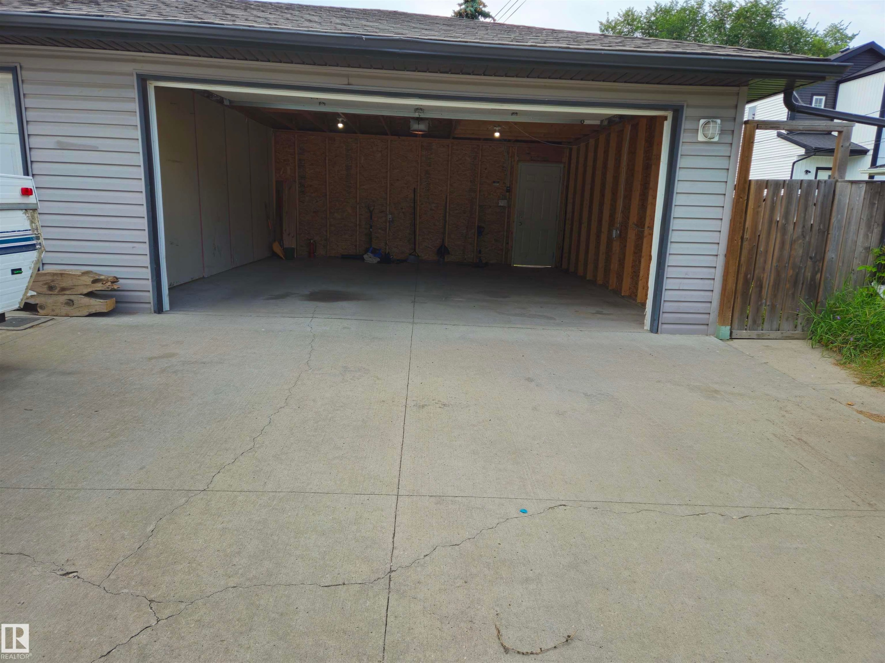 Attached garage with gray horizontal siding, asphalt shingle roof, and exposed wood stud framing - 11625 88 Street Nw, Edmonton, AB