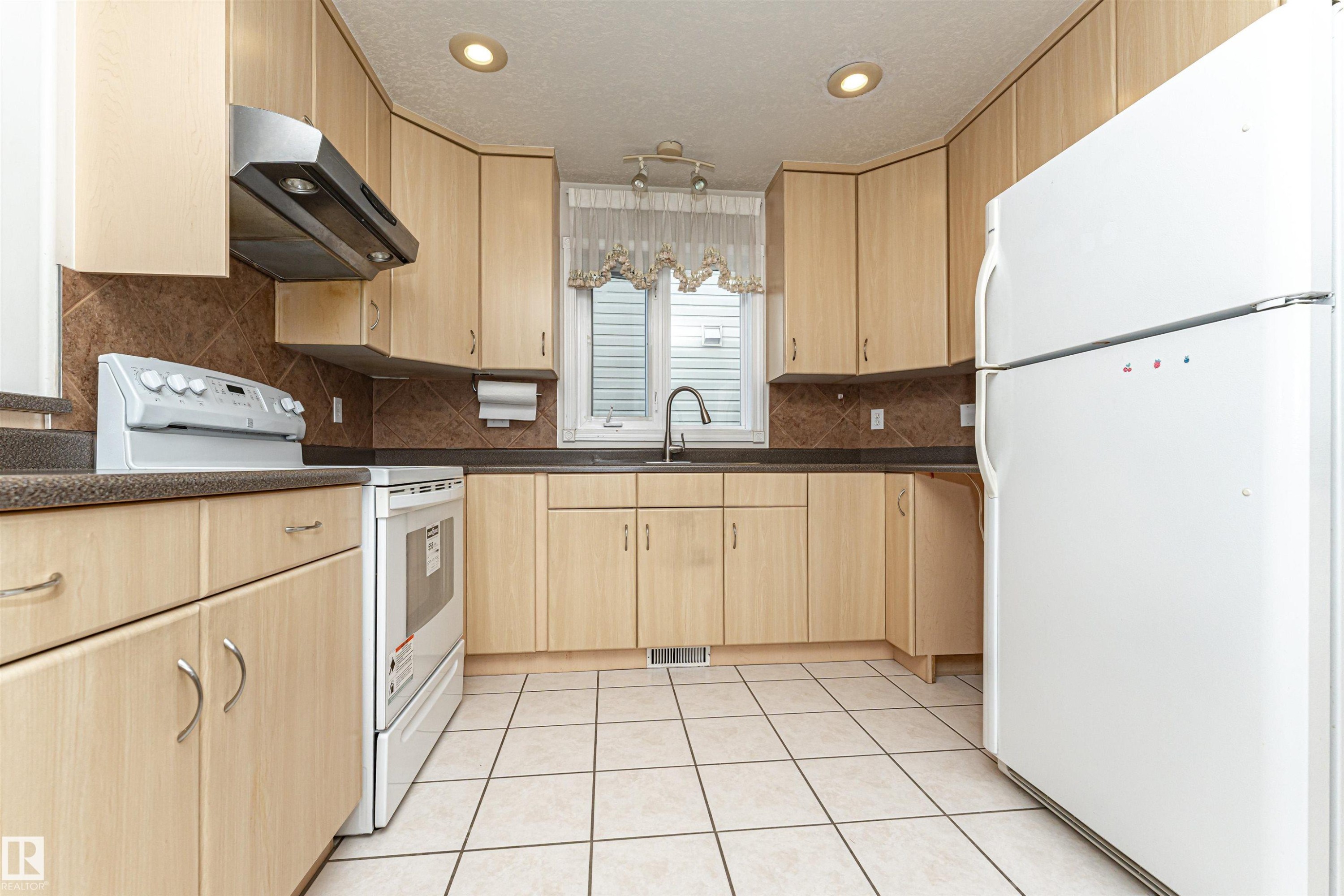 Kitchen featuring light wood-finish cabinetry, dark countertops, a tile backsplash, and recessed lighting - 12241 93 Street Nw, Edmonton, AB - Indoor Photo Showing Kitchen