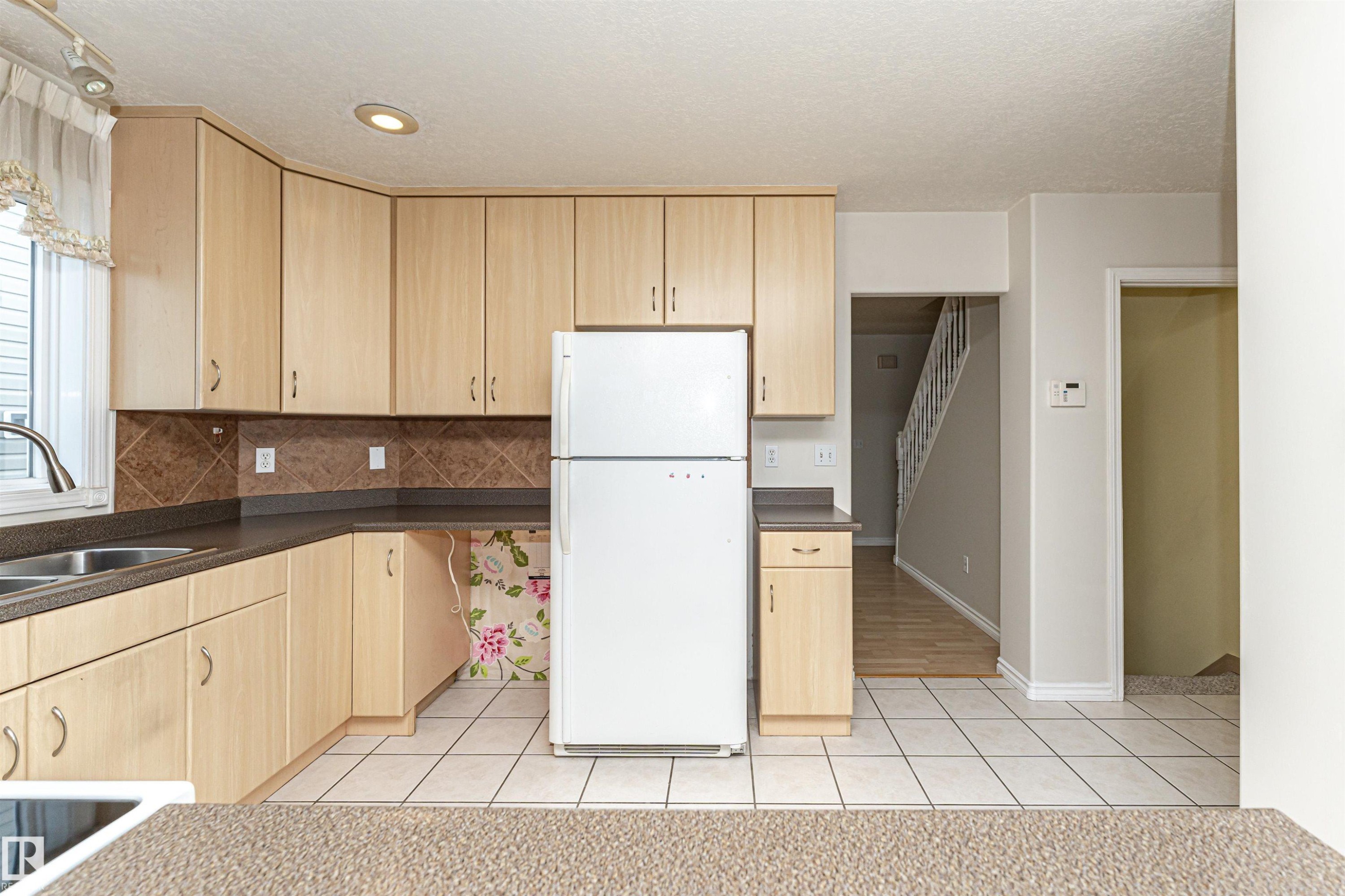 Light wood-finish cabinetry with dark countertops, a tile backsplash, and recessed lighting - 12241 93 Street Nw, Edmonton, AB - Indoor Photo Showing Kitchen
