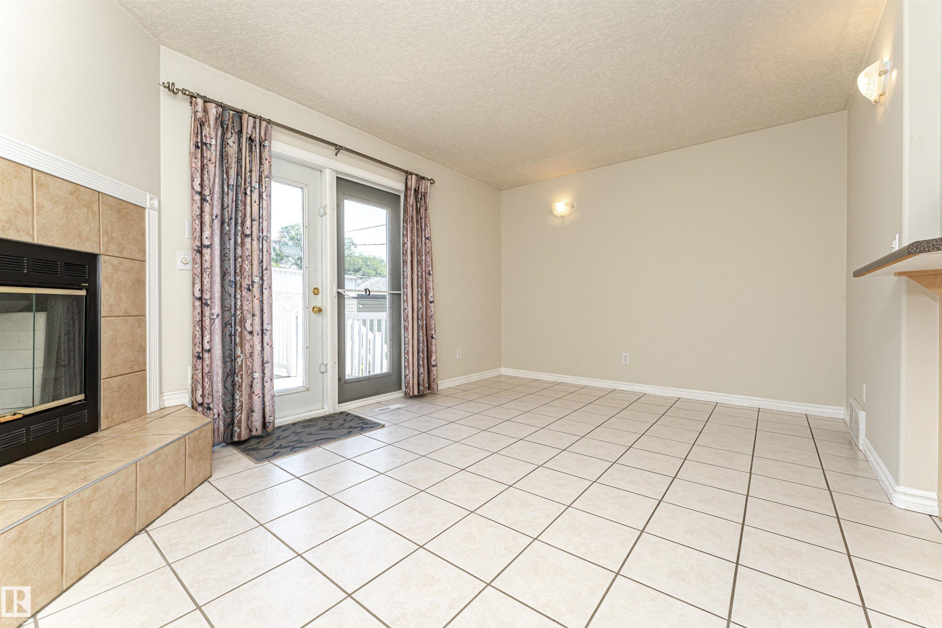 Tiled flooring, fireplace with tiled surround, and glass patio doors - 12241 93 Street Nw, Edmonton, AB - Indoor Photo Showing Other Room