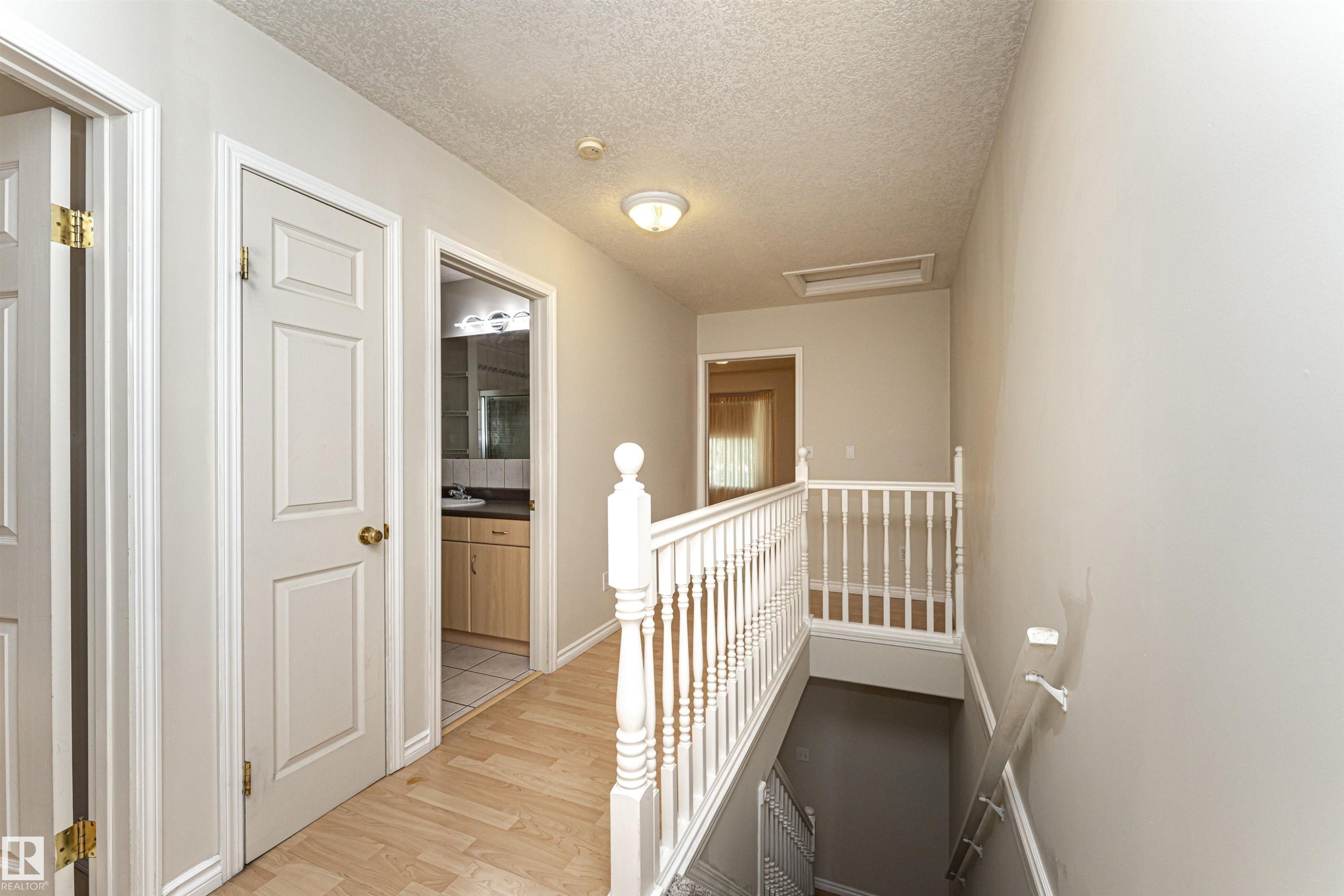Upper landing featuring wood-finish flooring, white panel doors, and a white baluster railing - 12241 93 Street Nw, Edmonton, AB - Indoor Photo Showing Other Room