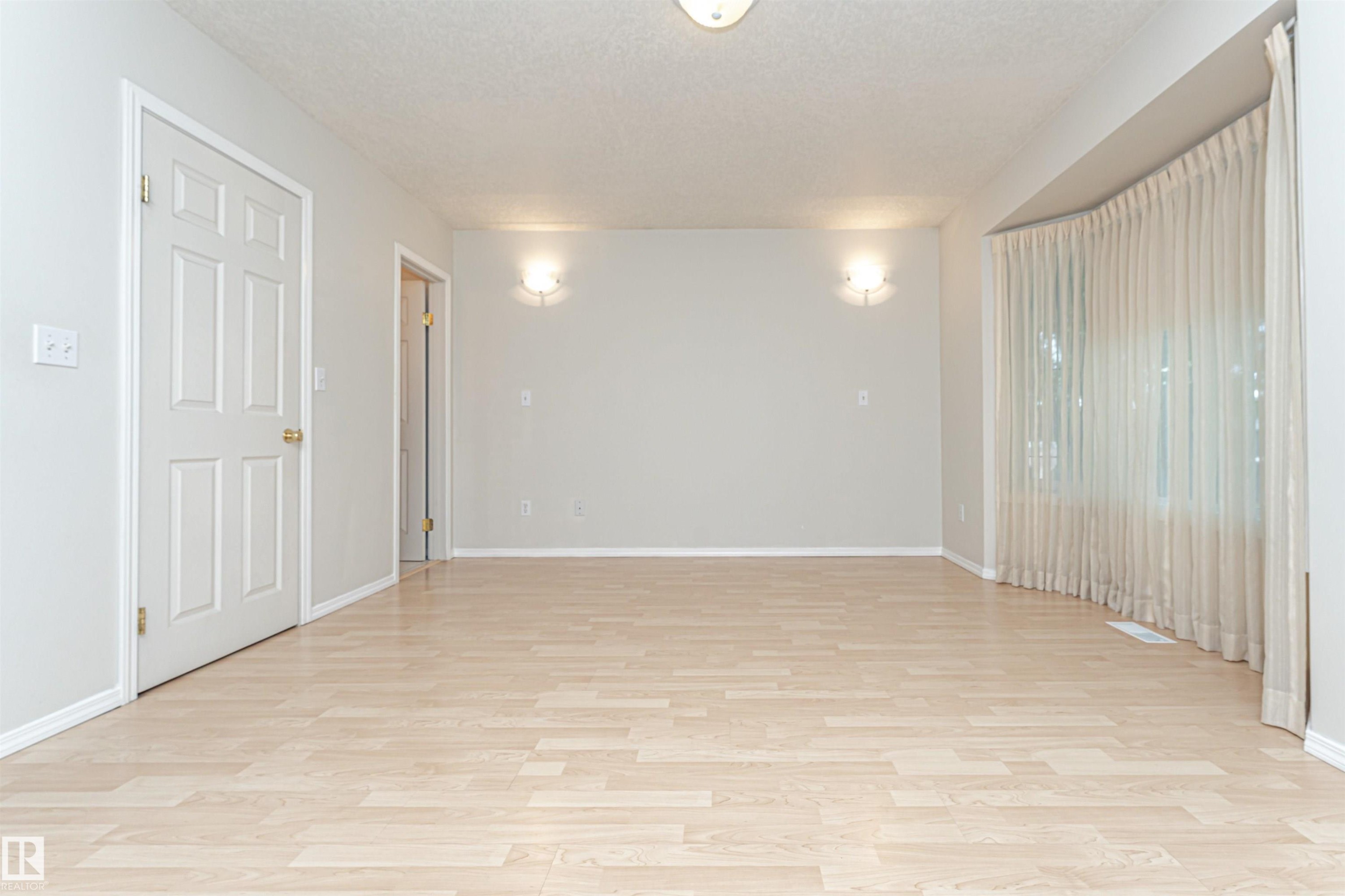 Light wood-finish flooring with a neutral wall color, recessed ceiling lighting, and two wall-mounted sconces - 12241 93 Street Nw, Edmonton, AB - Indoor Photo Showing Other Room