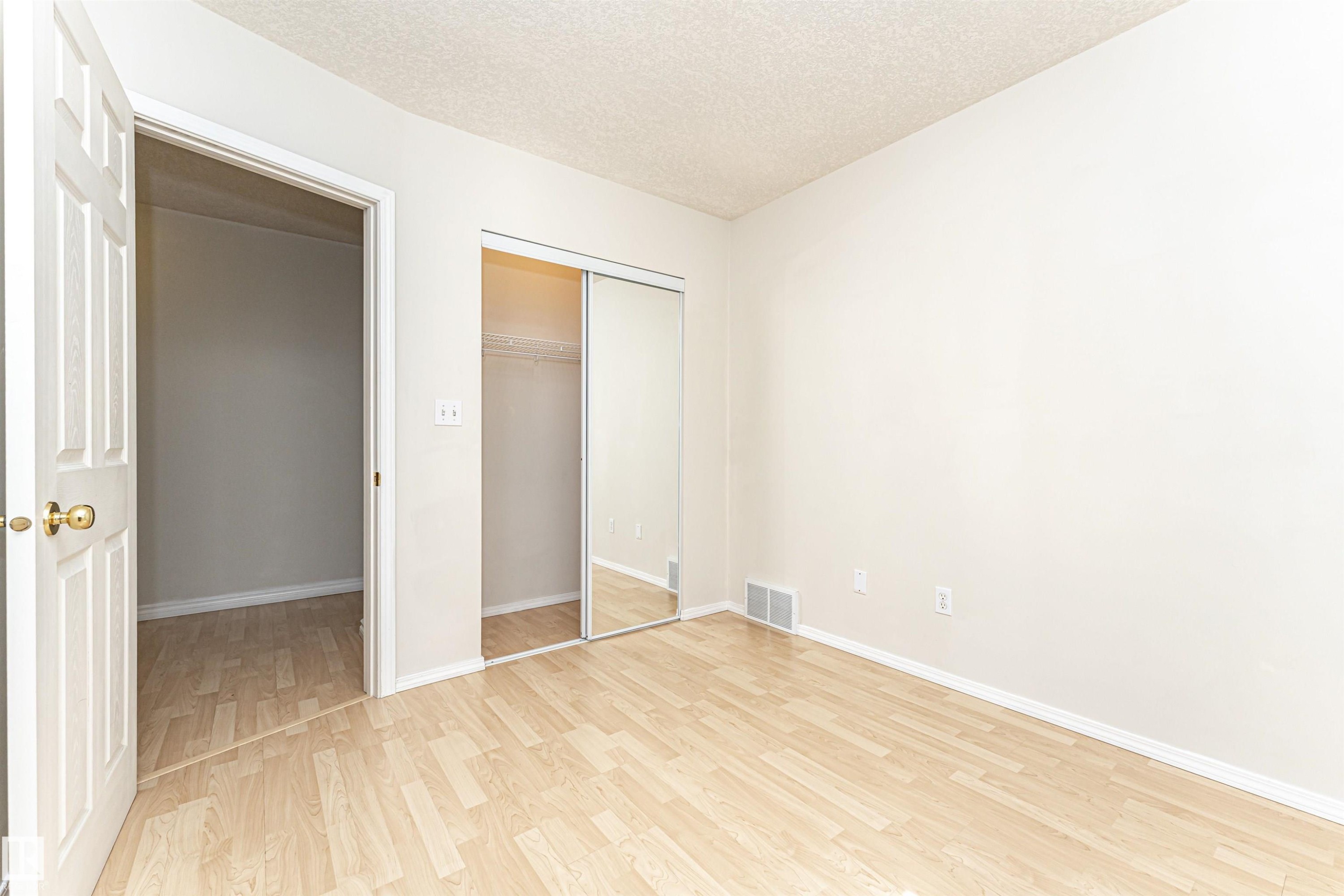 Light wood-finish flooring, mirrored sliding closet doors, and a neutral wall palette - 12241 93 Street Nw, Edmonton, AB - Indoor Photo Showing Other Room