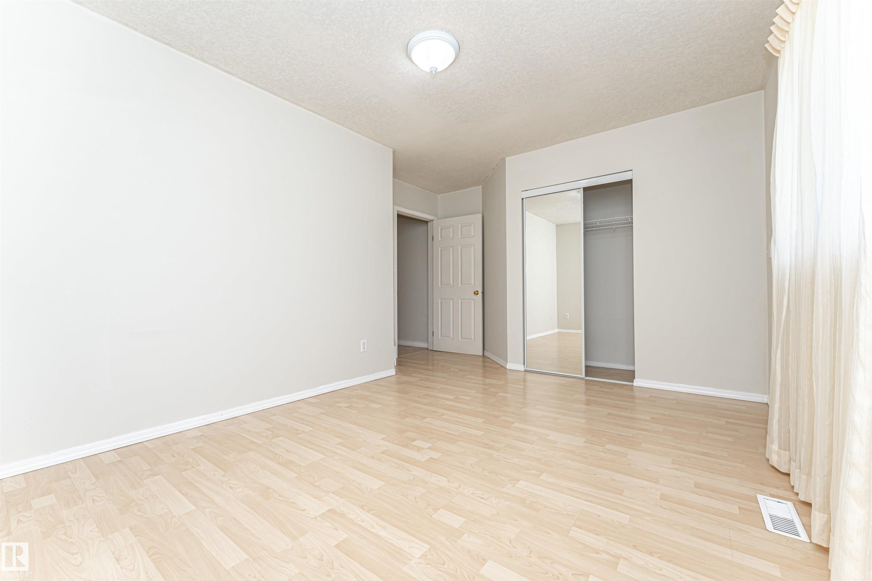 Light-toned wood-finish flooring, white walls, and a ceiling-mounted light fixture - 12241 93 Street Nw, Edmonton, AB - Indoor Photo Showing Other Room