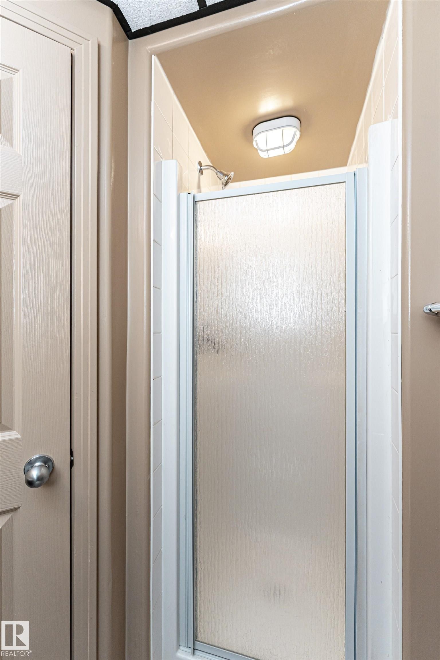 Shower enclosure with textured glass paneling and a chrome shower head - 12241 93 Street Nw, Edmonton, AB - Indoor Photo Showing Bathroom
