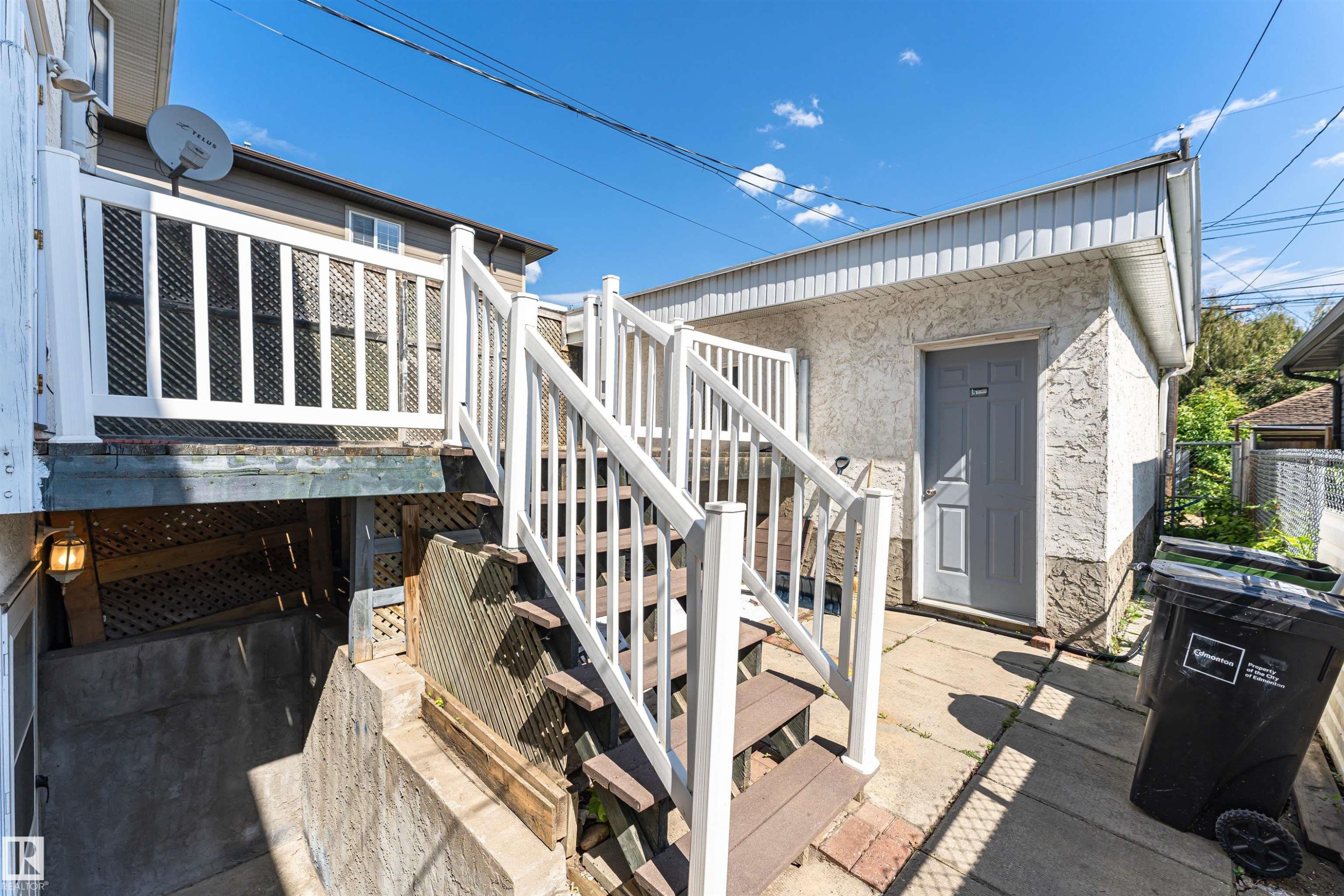Exterior features include a white-painted wood balustrade, wood-finish stair treads, and a concrete patio - 12241 93 Street Nw, Edmonton, AB - Outdoor With Exterior