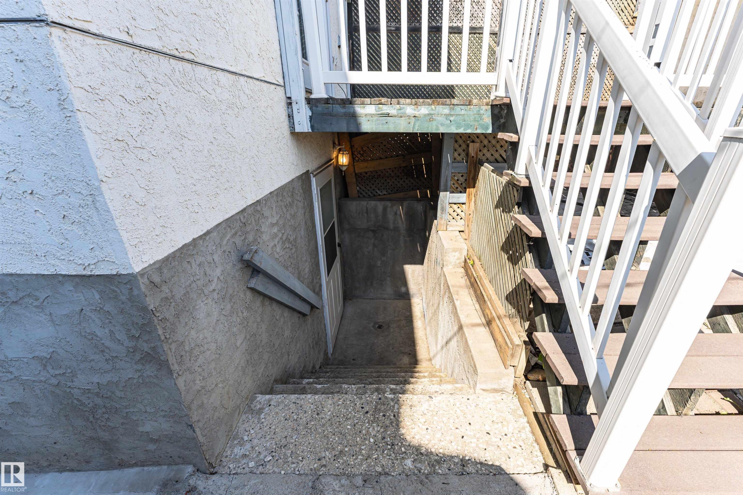 Exterior with textured stucco siding, concrete stairs, and a white deck railing - 12241 93 Street Nw, Edmonton, AB - Outdoor