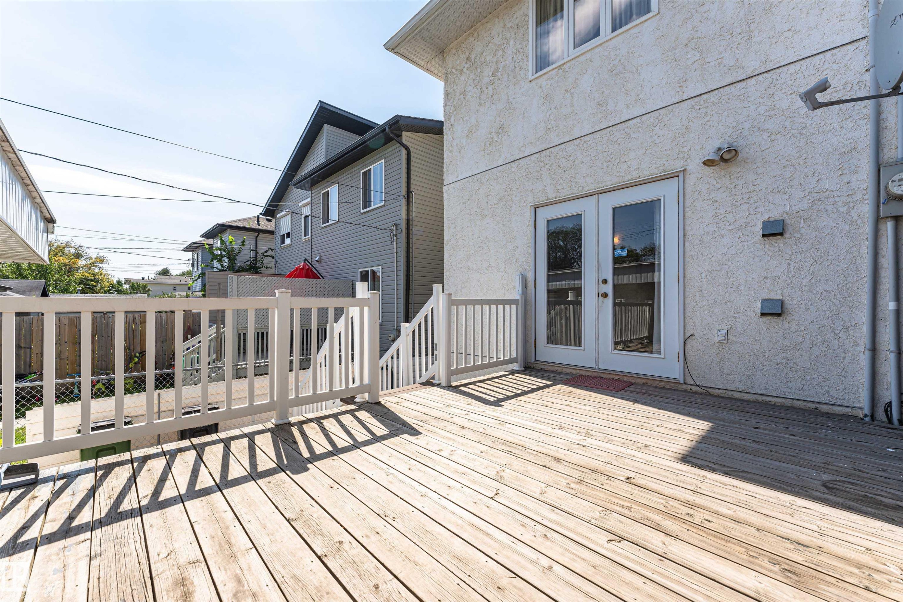 Spacious wood deck with white railing, double glass-paneled doors, and textured exterior siding - 12241 93 Street Nw, Edmonton, AB - Outdoor With Deck Patio Veranda With Exterior