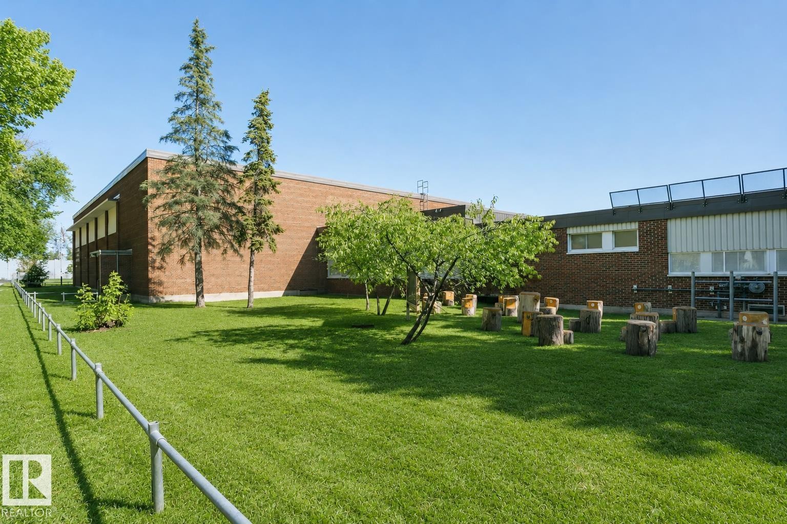Expansive green space with mature trees, brick exterior, and a metal railing - 12241 93 Street Nw, Edmonton, AB - Outdoor