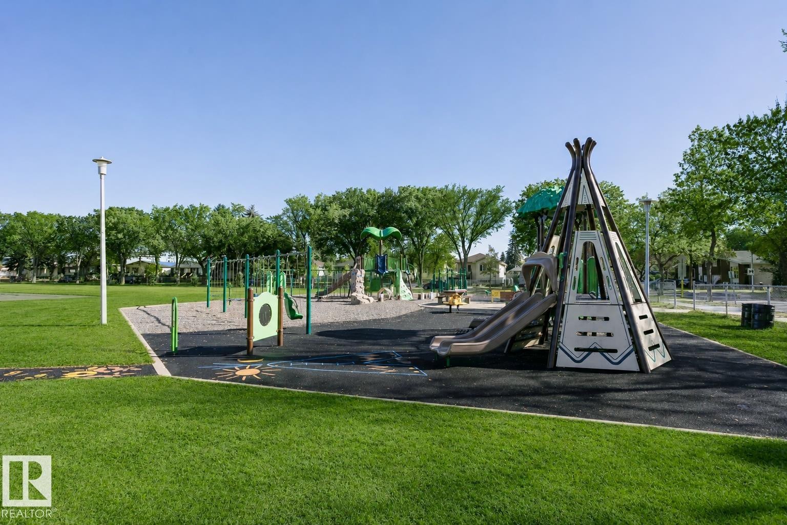Expansive green space featuring a dedicated playground area with multiple play structures, a slide, and swings - 12241 93 Street Nw, Edmonton, AB - Outdoor