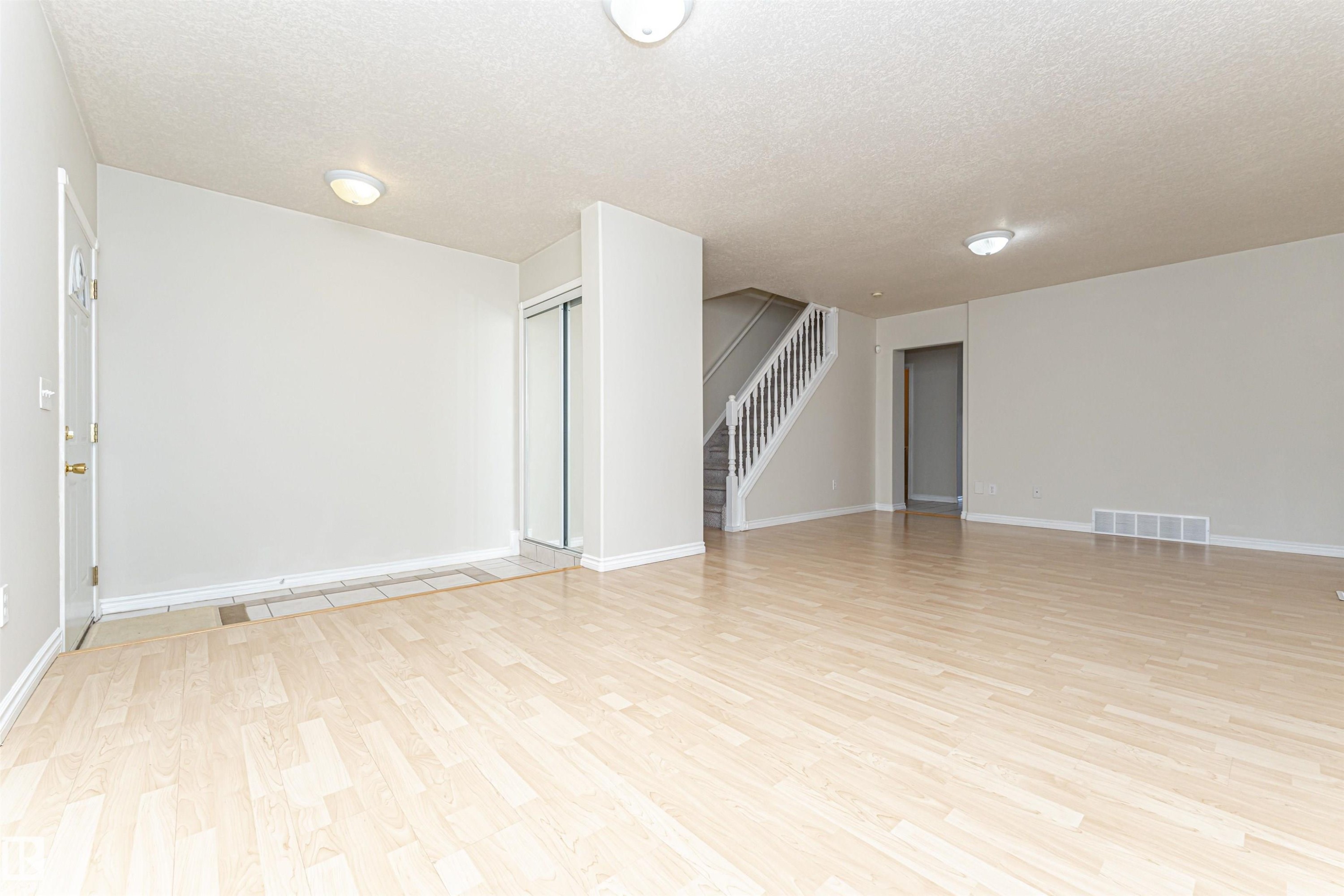 Wood-finish flooring, staircase with white risers, flush-mount lighting, and mirrored closet doors - 12241 93 Street Nw, Edmonton, AB - Indoor Photo Showing Other Room