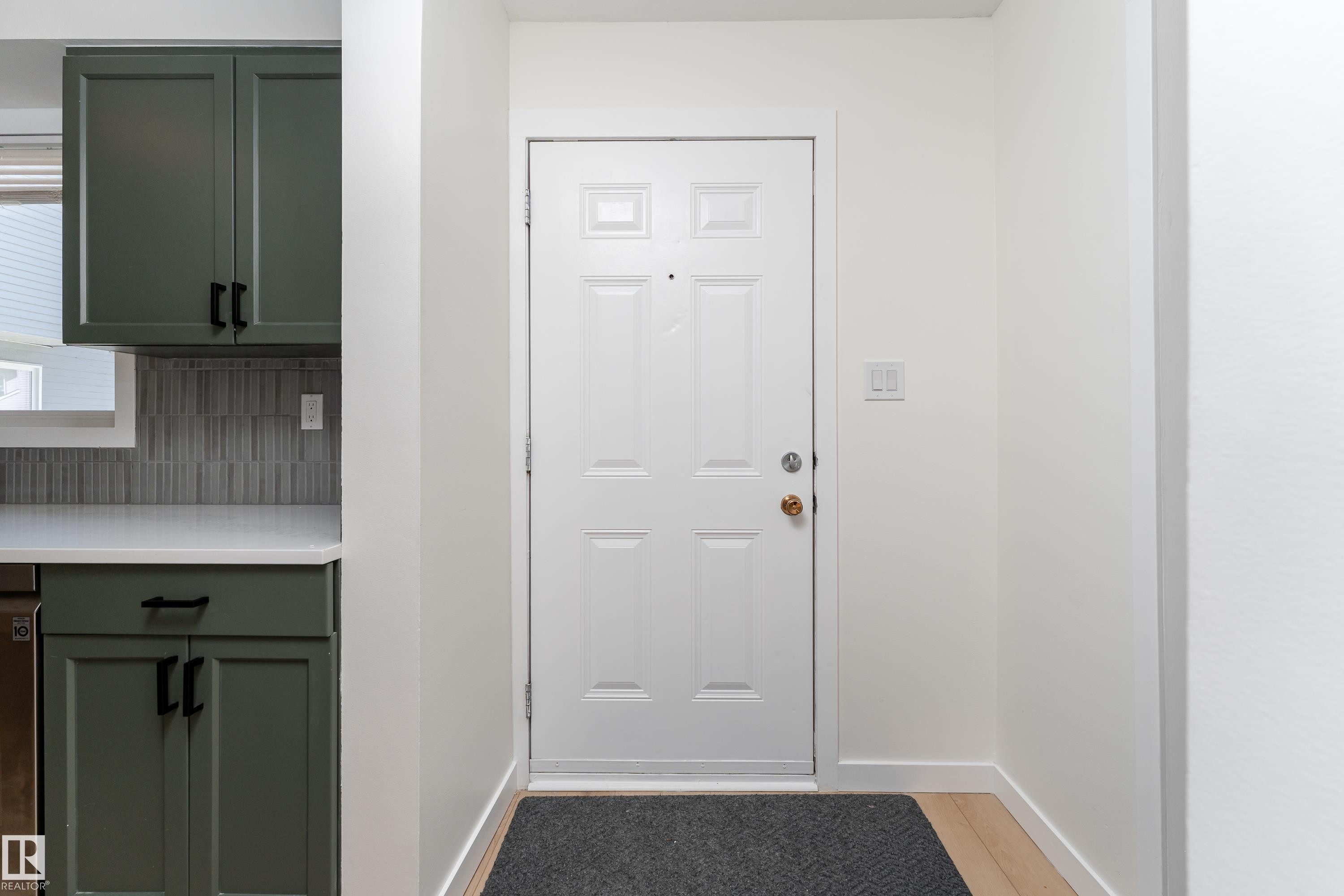 Entryway featuring a paneled door with brass hardware and light wood-finish flooring - #10 1415 62 St Nw, Edmonton, AB - Indoor Photo Showing Other Room