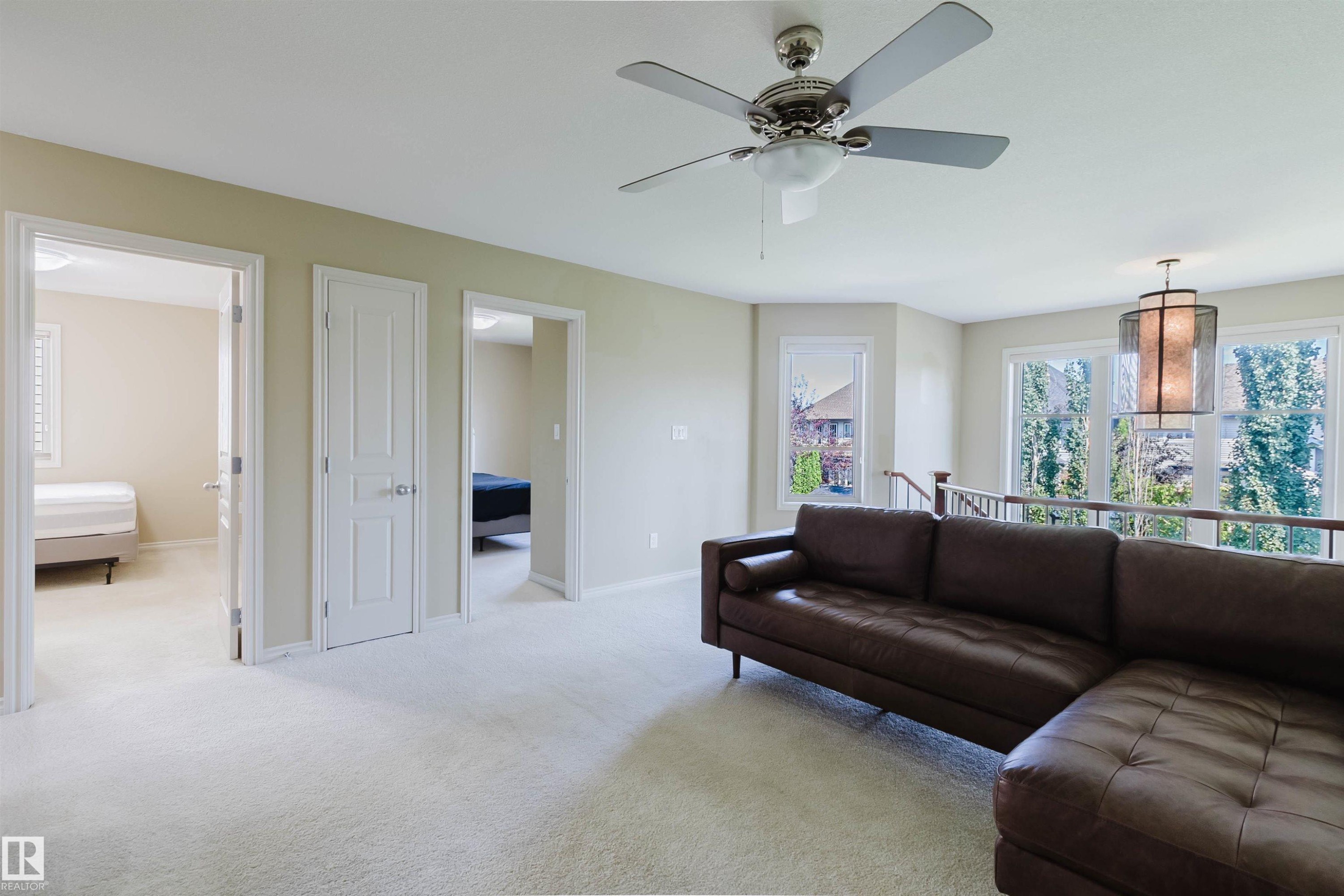 Carpeted open area featuring multiple windows, a ceiling fan, and a decorative pendant light fixture - 864 Armitage Wynd Sw, Edmonton, AB - Indoor Photo Showing Living Room
