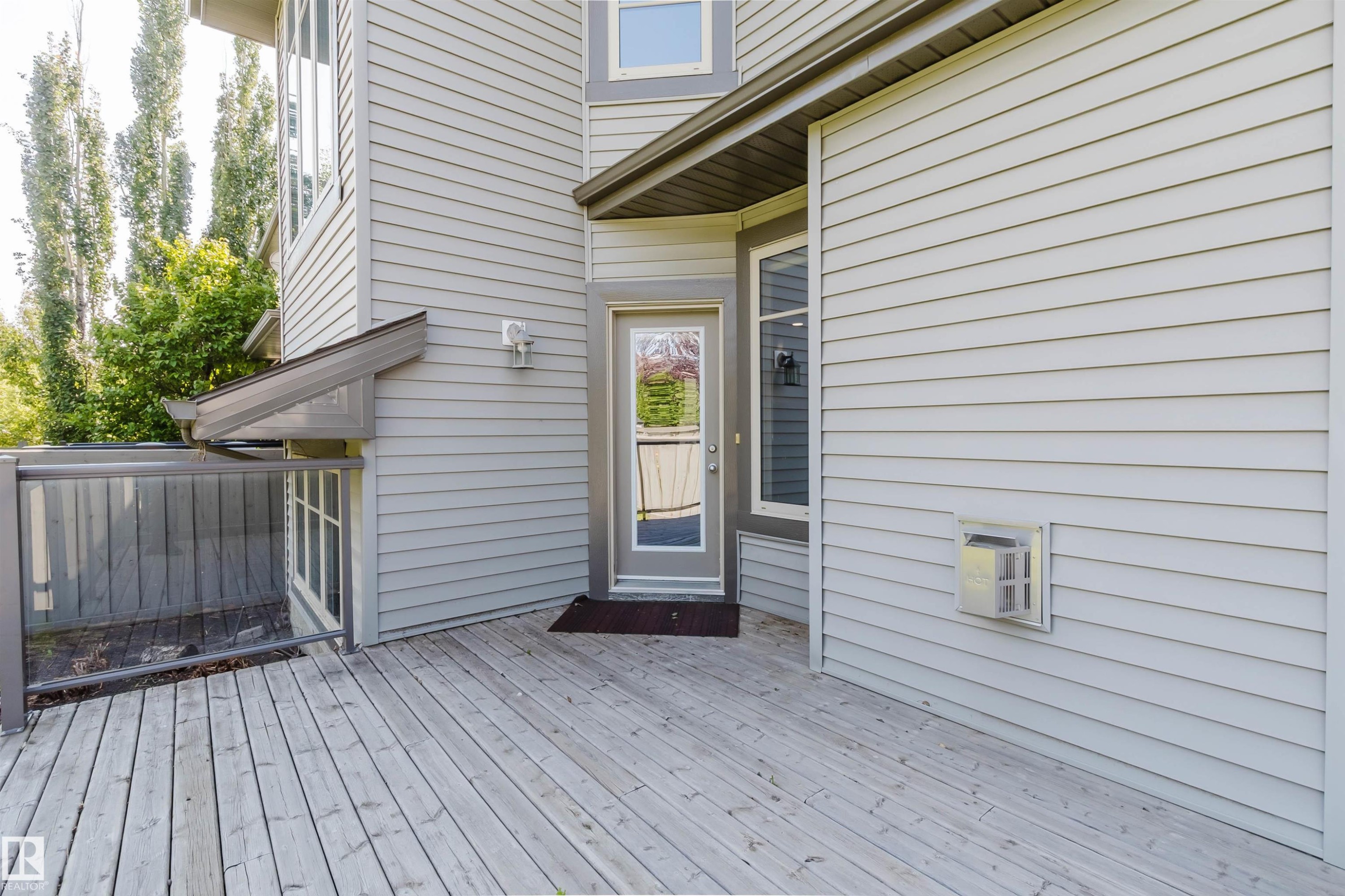 Expansive outdoor deck with wood-finish planks, clear glass panel railings, and direct access to the interior - 864 Armitage Wynd Sw, Edmonton, AB - Outdoor With Deck Patio Veranda With Exterior