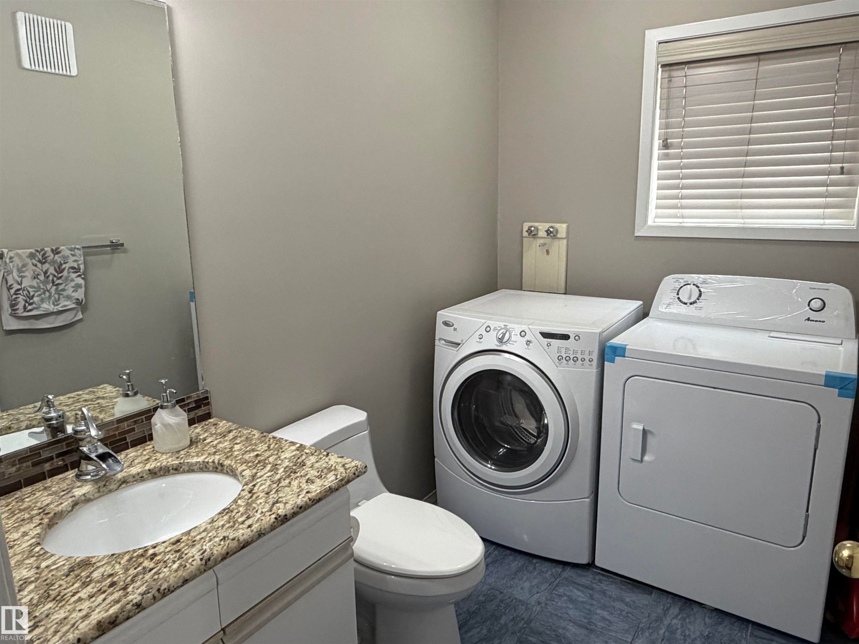 Vanity with granite countertop, integrated sink, and mosaic tile backsplash - 1535 80A Street Nw, Edmonton, AB - Indoor Photo Showing Laundry Room
