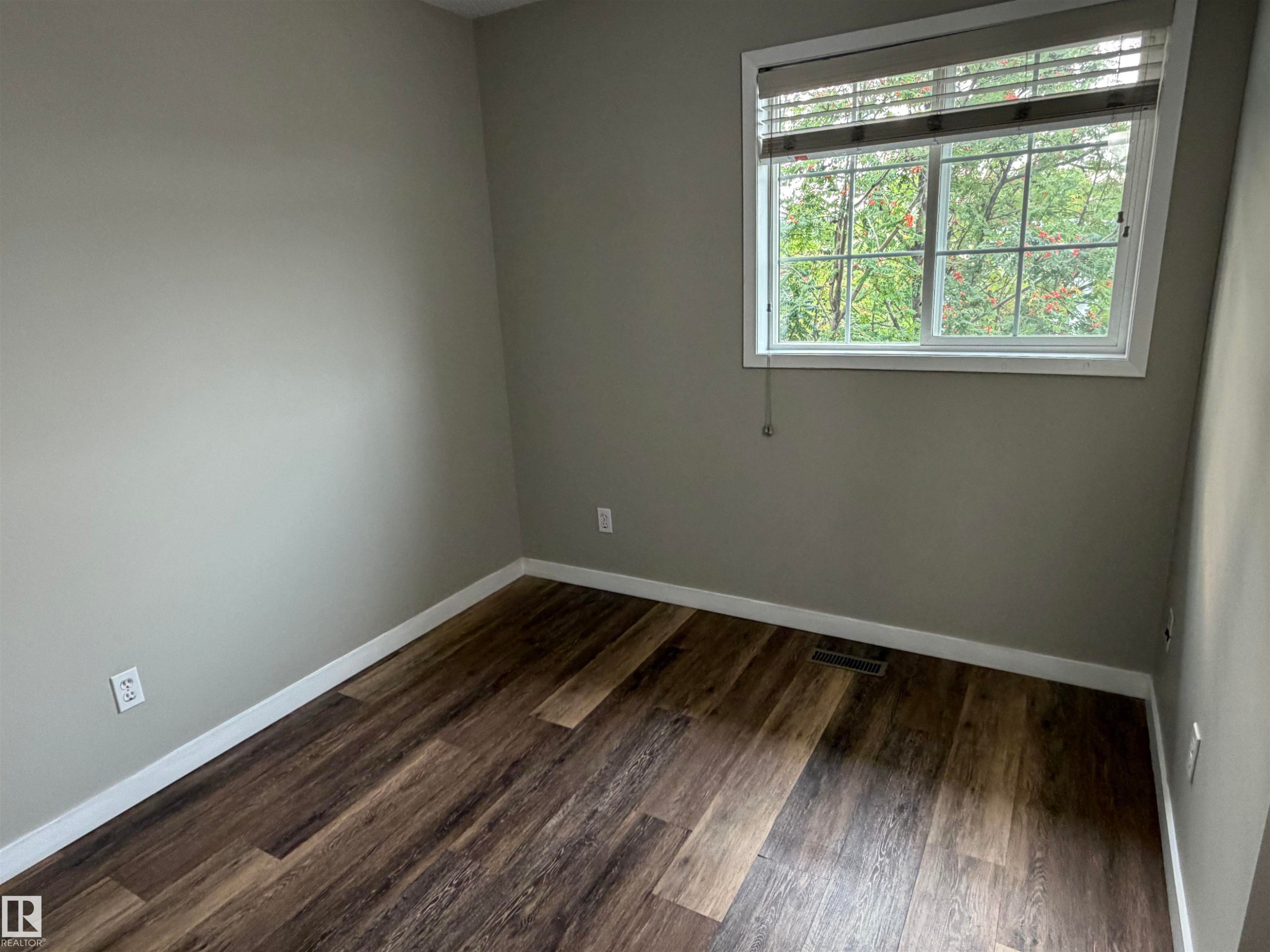 Wood-finish flooring, neutral wall tones, white trim, and a window with blinds - 1535 80A Street Nw, Edmonton, AB - Indoor Photo Showing Other Room