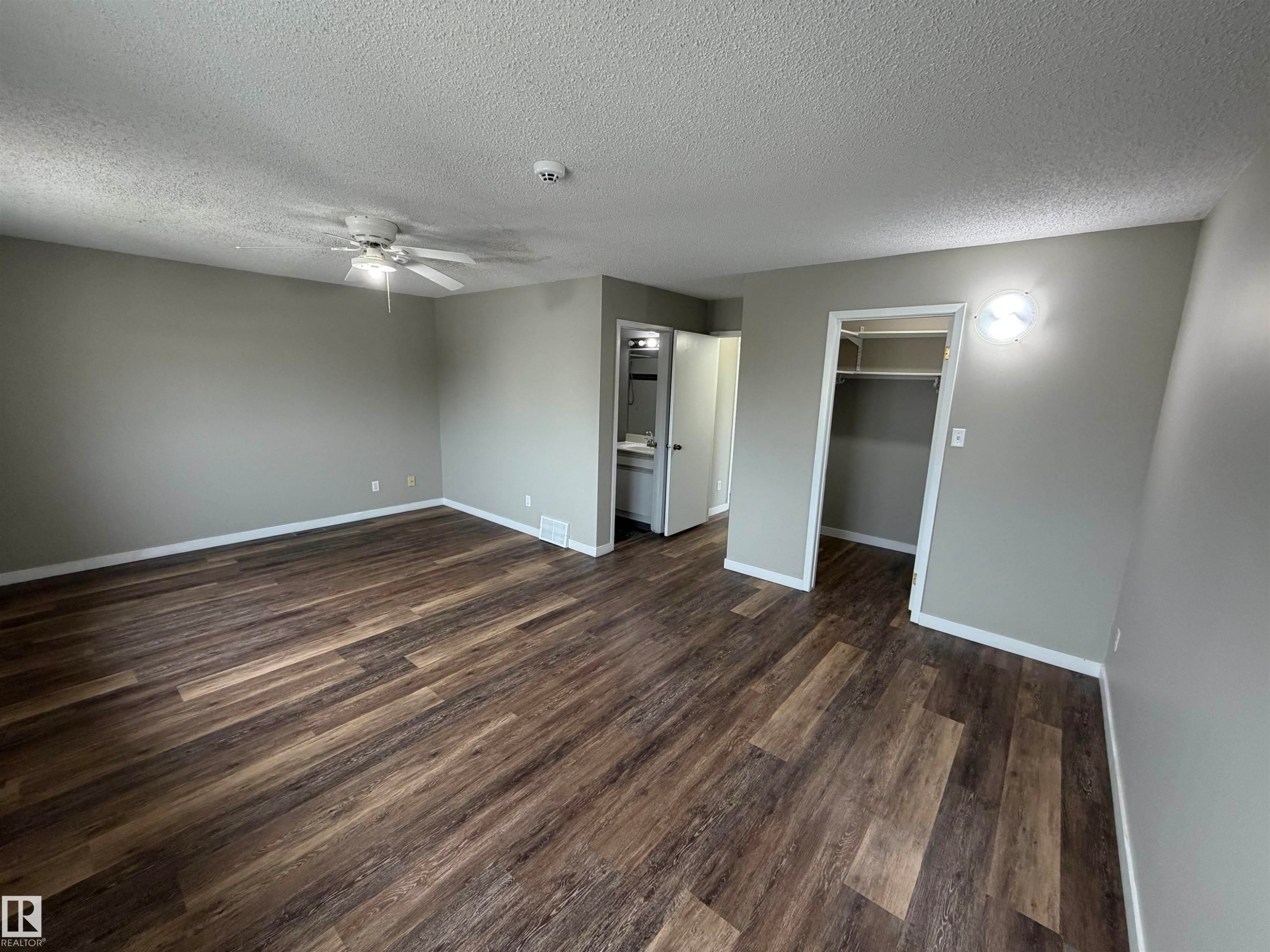 Spacious room with wood-finish flooring, neutral gray walls, and a ceiling fan - 1535 80A Street Nw, Edmonton, AB - Indoor Photo Showing Other Room