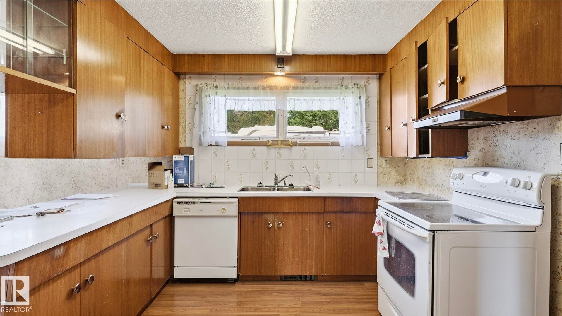 Wood-finish cabinetry paired with white countertops and a tile backsplash - 52012 Hwy 21, Rural Strathcona County, AB - Indoor Photo Showing Kitchen With Double Sink